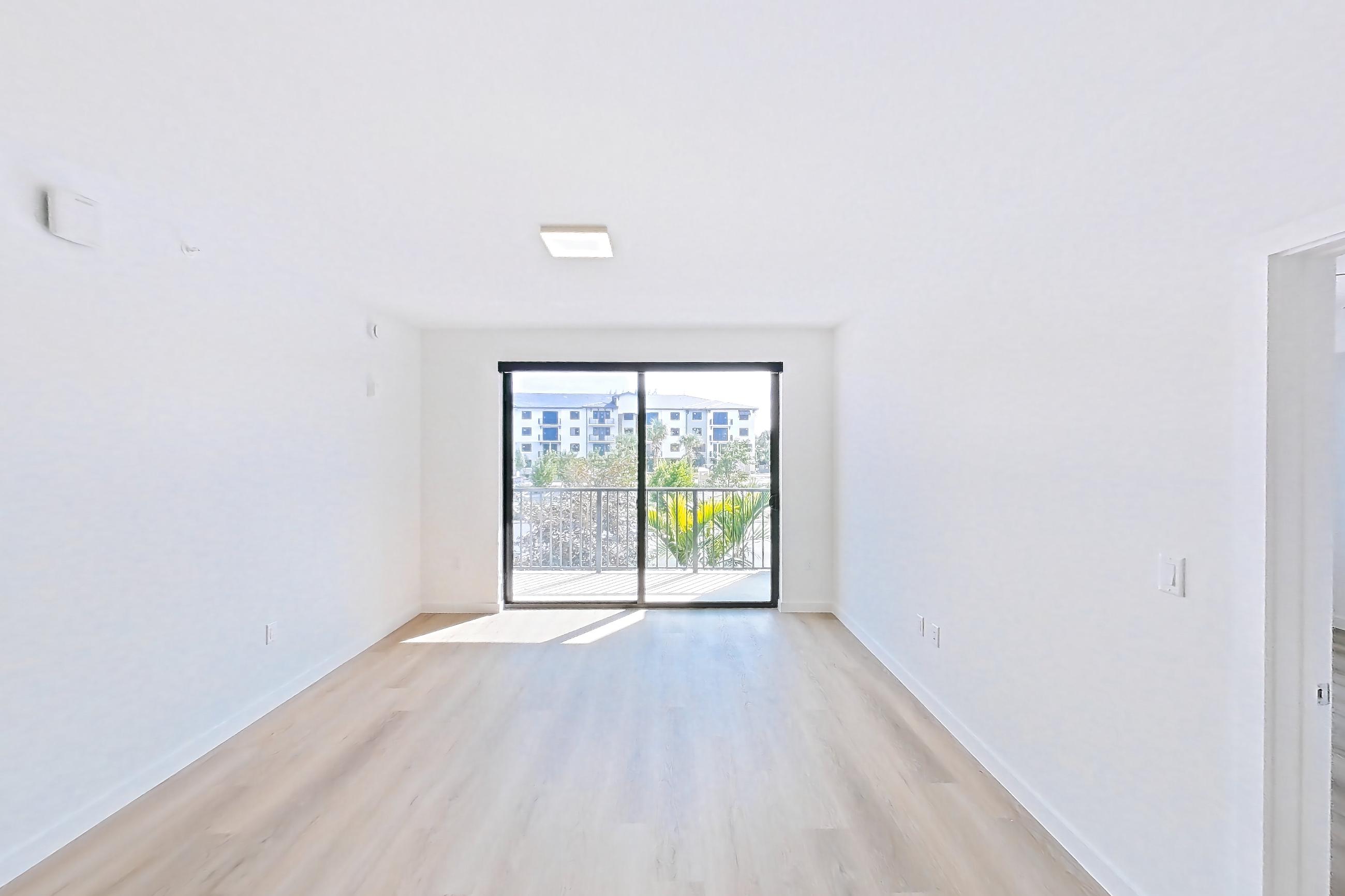 Living space with electric range, light countertops, light wood-finish flooring, oven/range, and stainless steel appliances, Apartment 208 at Caroline Pompano Beach