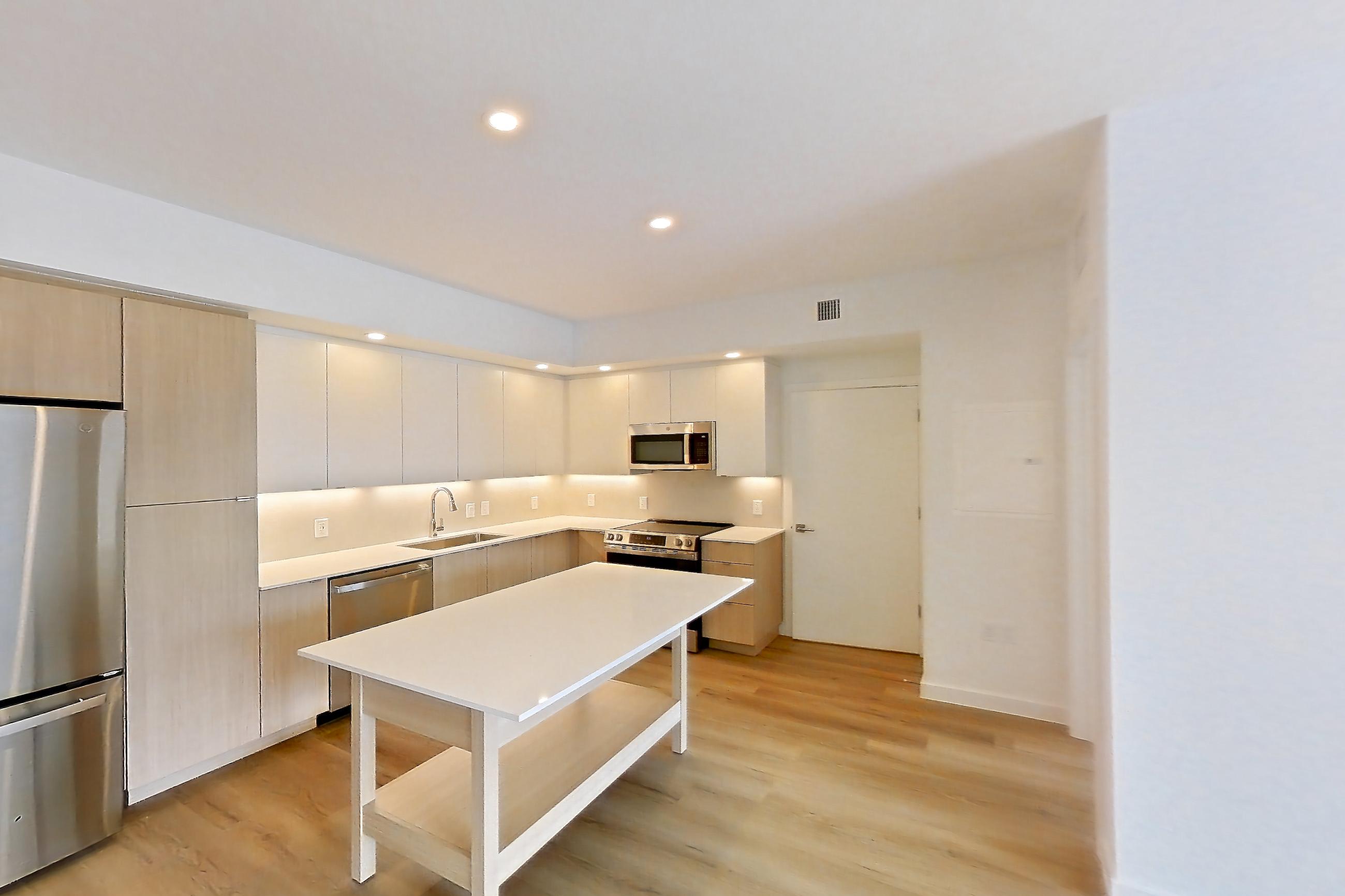 Living space with electric range, light countertops, light wood-finish flooring, oven/range, and stainless steel appliances, Apartment 208 at Caroline Pompano Beach
