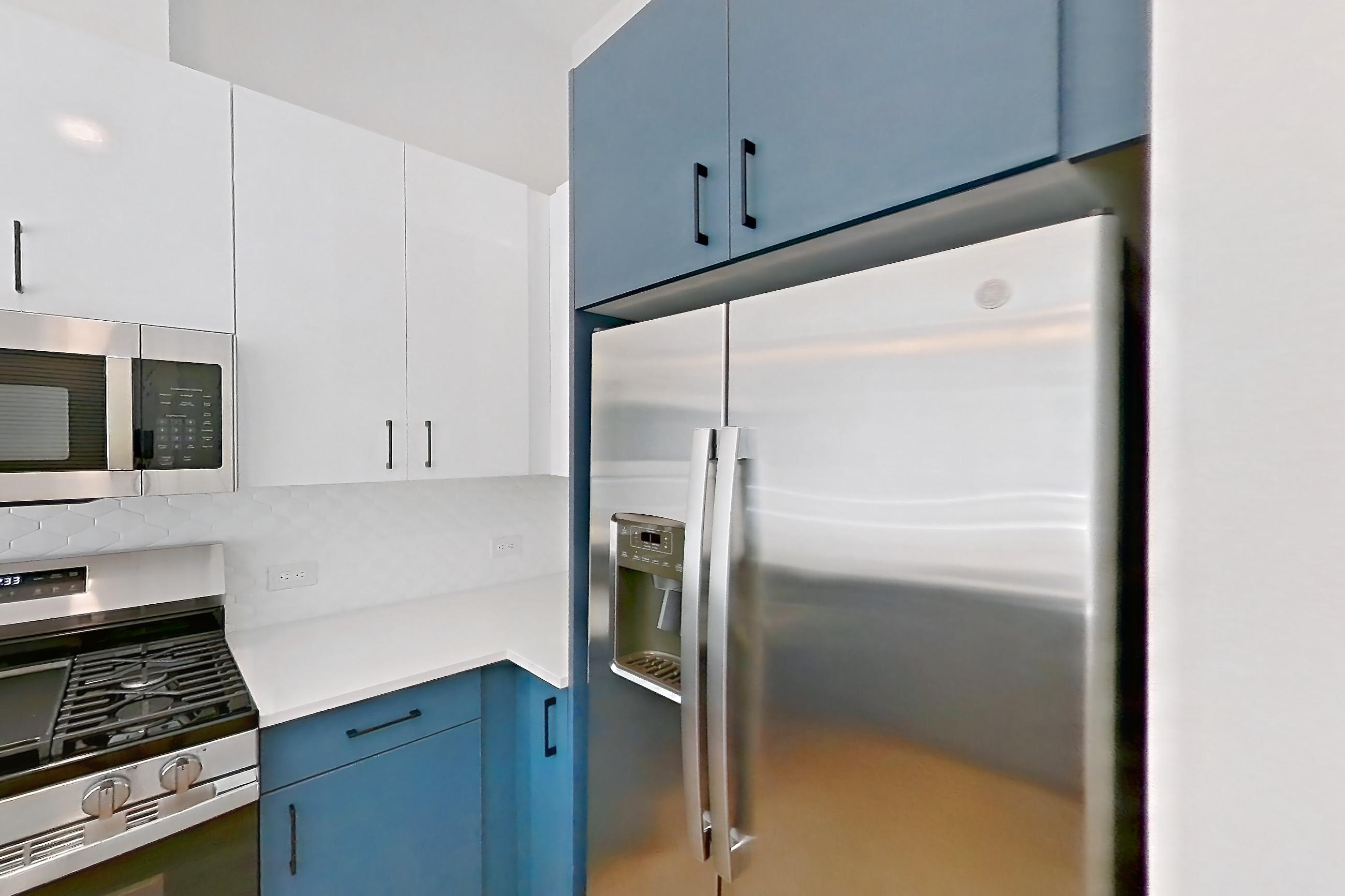 Kitchen with dishwasher, gas range, light countertops, light stone countertops, light wood-finish flooring, microwave, oven/range, refrigerator, stainless steel appliances, and water & ice dispenser, Apartment 120 at Bria