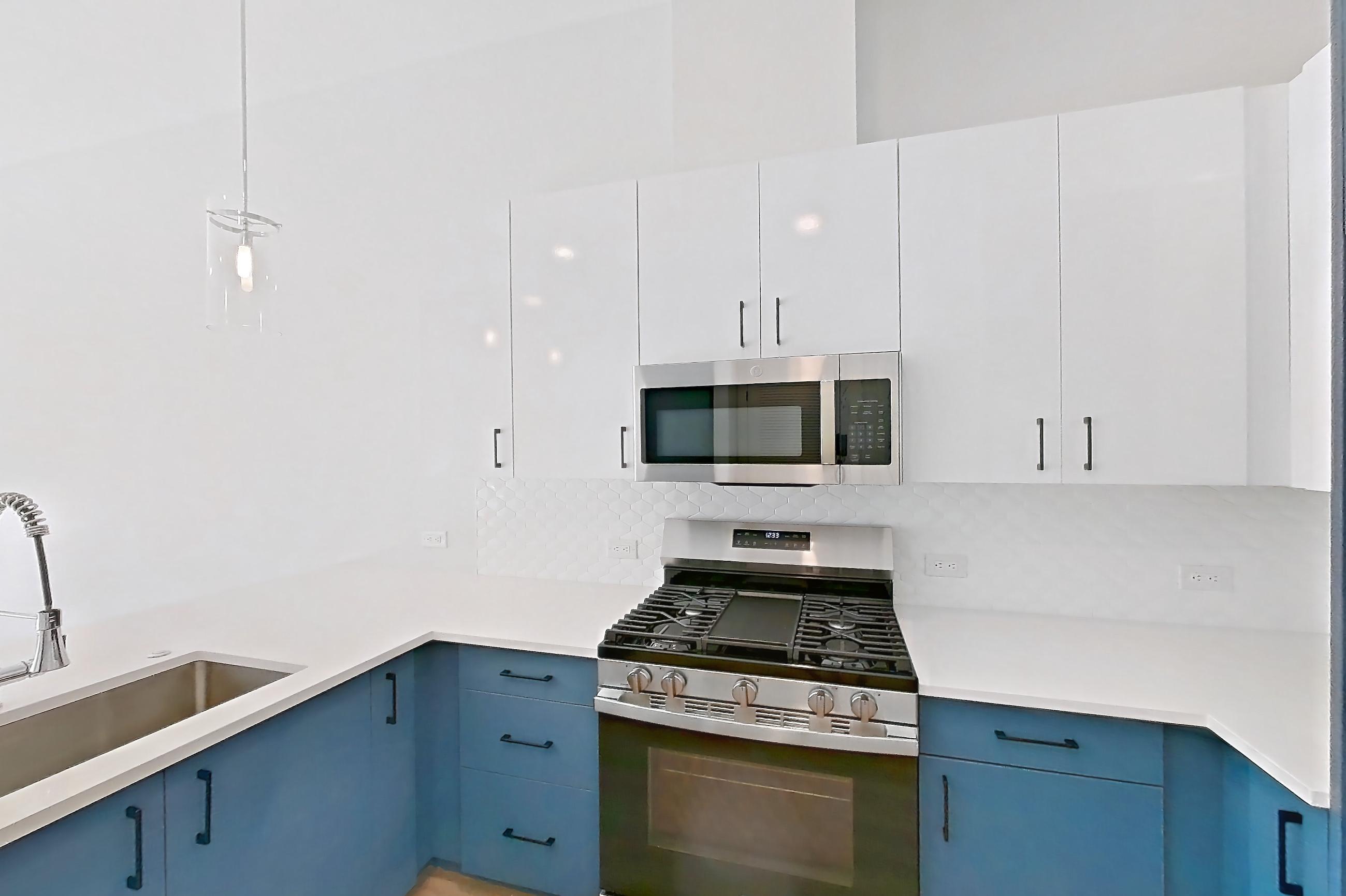 Kitchen with dishwasher, gas range, light countertops, light stone countertops, light wood-finish flooring, microwave, oven/range, refrigerator, stainless steel appliances, and water & ice dispenser, Apartment 120 at Bria
