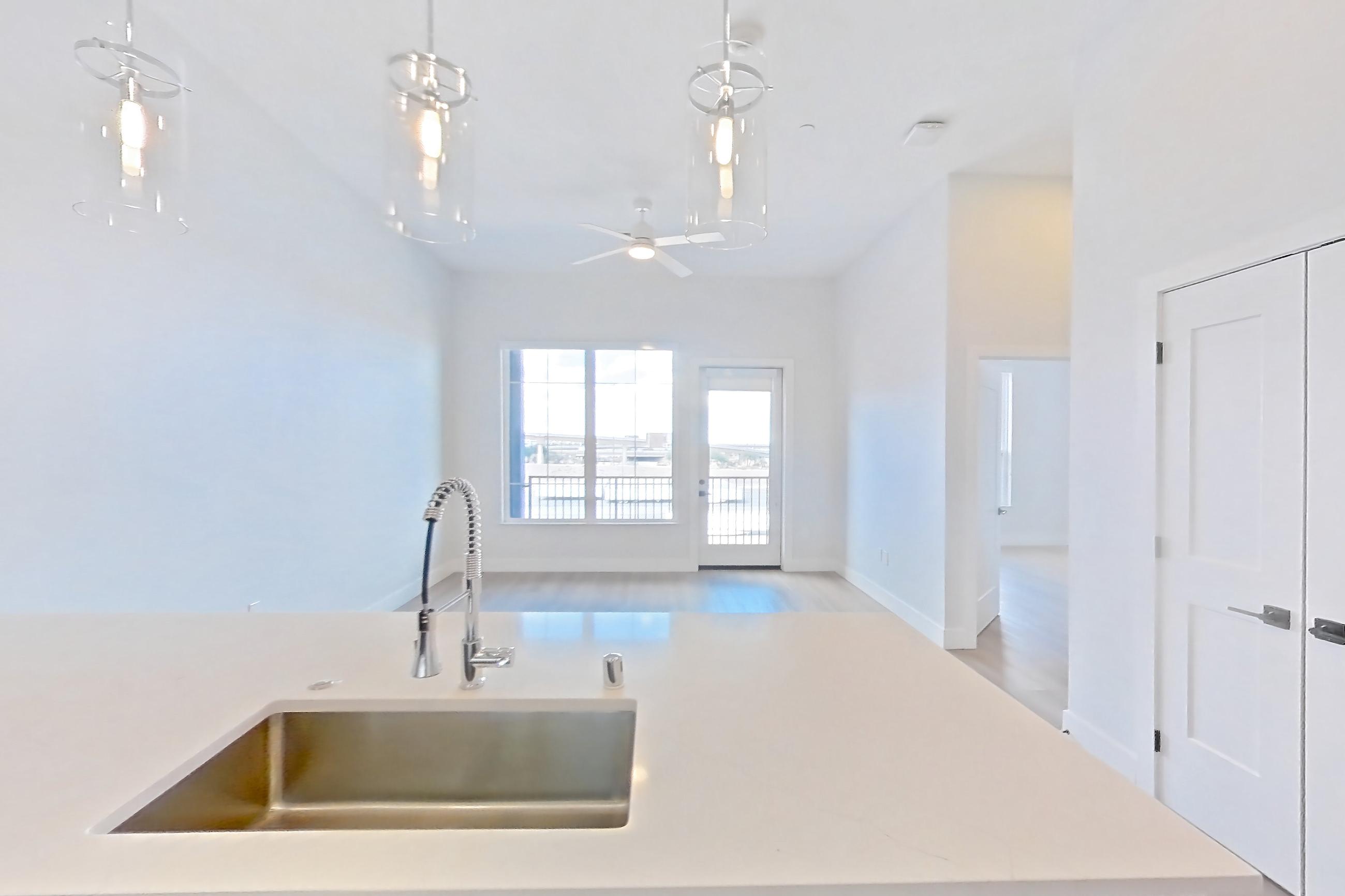 Kitchen with dishwasher, gas range, light countertops, light stone countertops, light wood-finish flooring, microwave, oven/range, refrigerator, stainless steel appliances, and water & ice dispenser, Apartment 568 at Bria