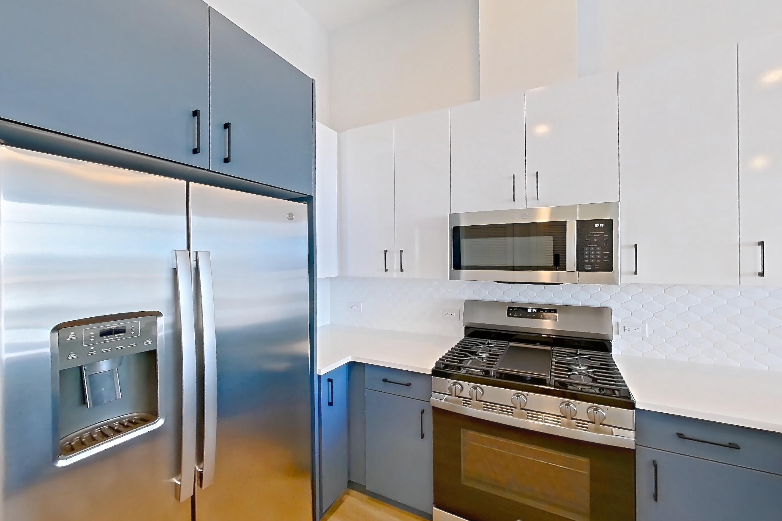 Kitchen with dishwasher, gas range, light countertops, light stone countertops, light wood-finish flooring, microwave, oven/range, refrigerator, stainless steel appliances, and water & ice dispenser, Apartment 568 at Bria