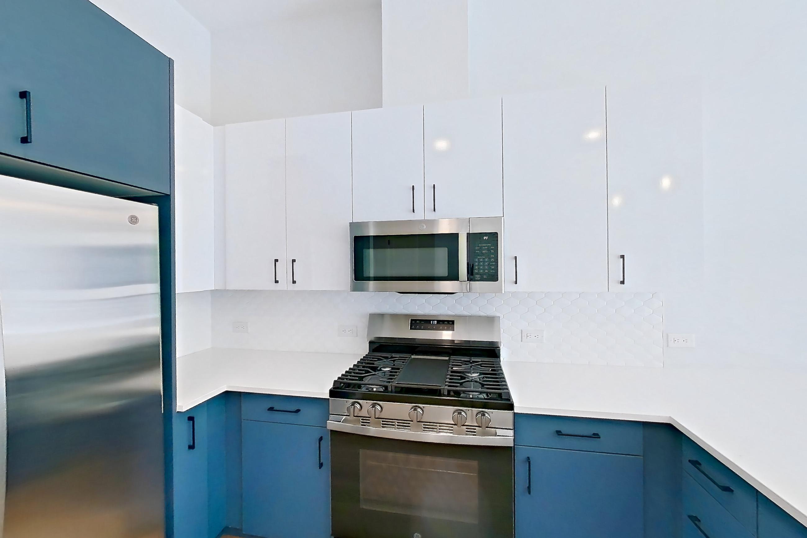 Kitchen with dishwasher, gas range, light countertops, light stone countertops, light wood-finish flooring, microwave, oven/range, refrigerator, stainless steel appliances, and water & ice dispenser, Apartment 130 at Bria