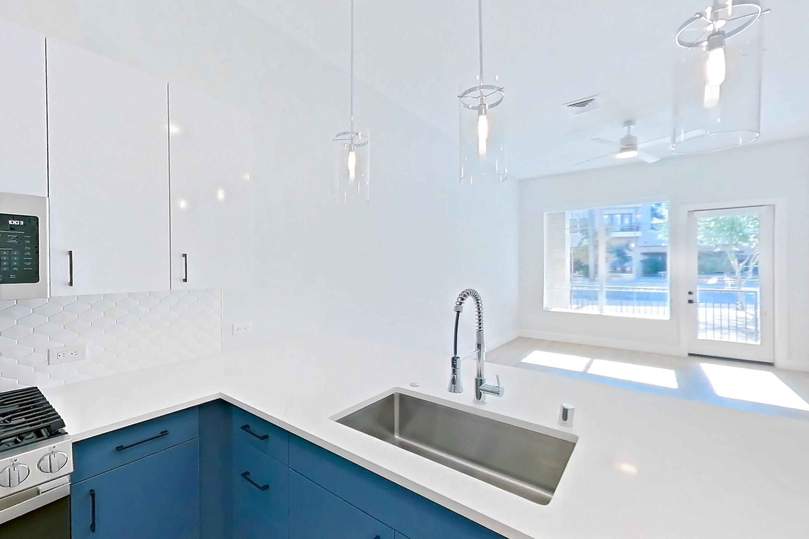 Kitchen with dishwasher, gas range, kitchen island, light countertops, light stone countertops, light wood-finish flooring, microwave, oven/range, refrigerator, stainless steel appliances, and water & ice dispenser, Apartment 116 at Bria