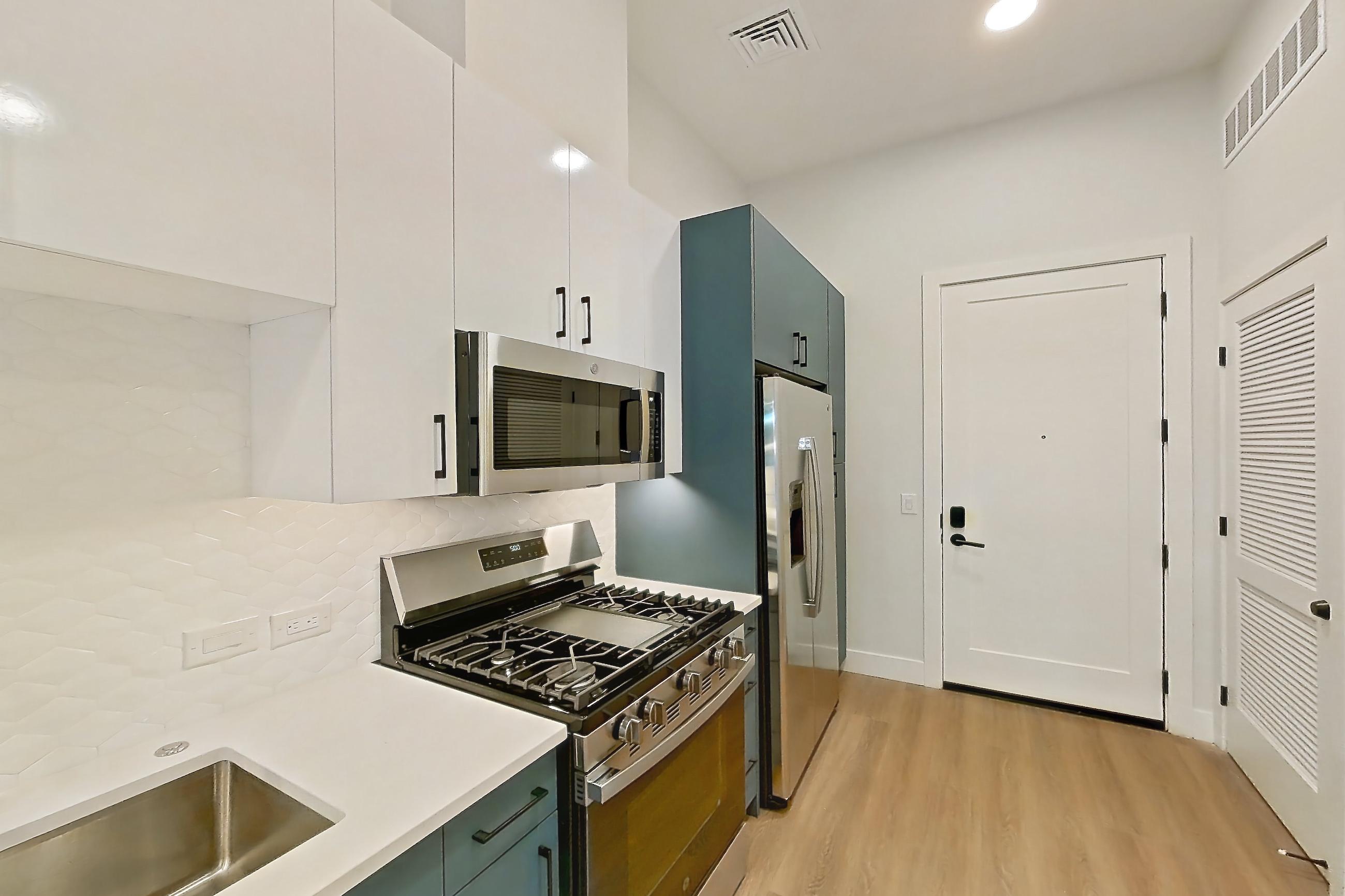 Kitchen with dishwasher, gas range, light countertops, light stone countertops, light wood-finish flooring, microwave, oven/range, refrigerator, and stainless steel appliances, Apartment 113 at Bria