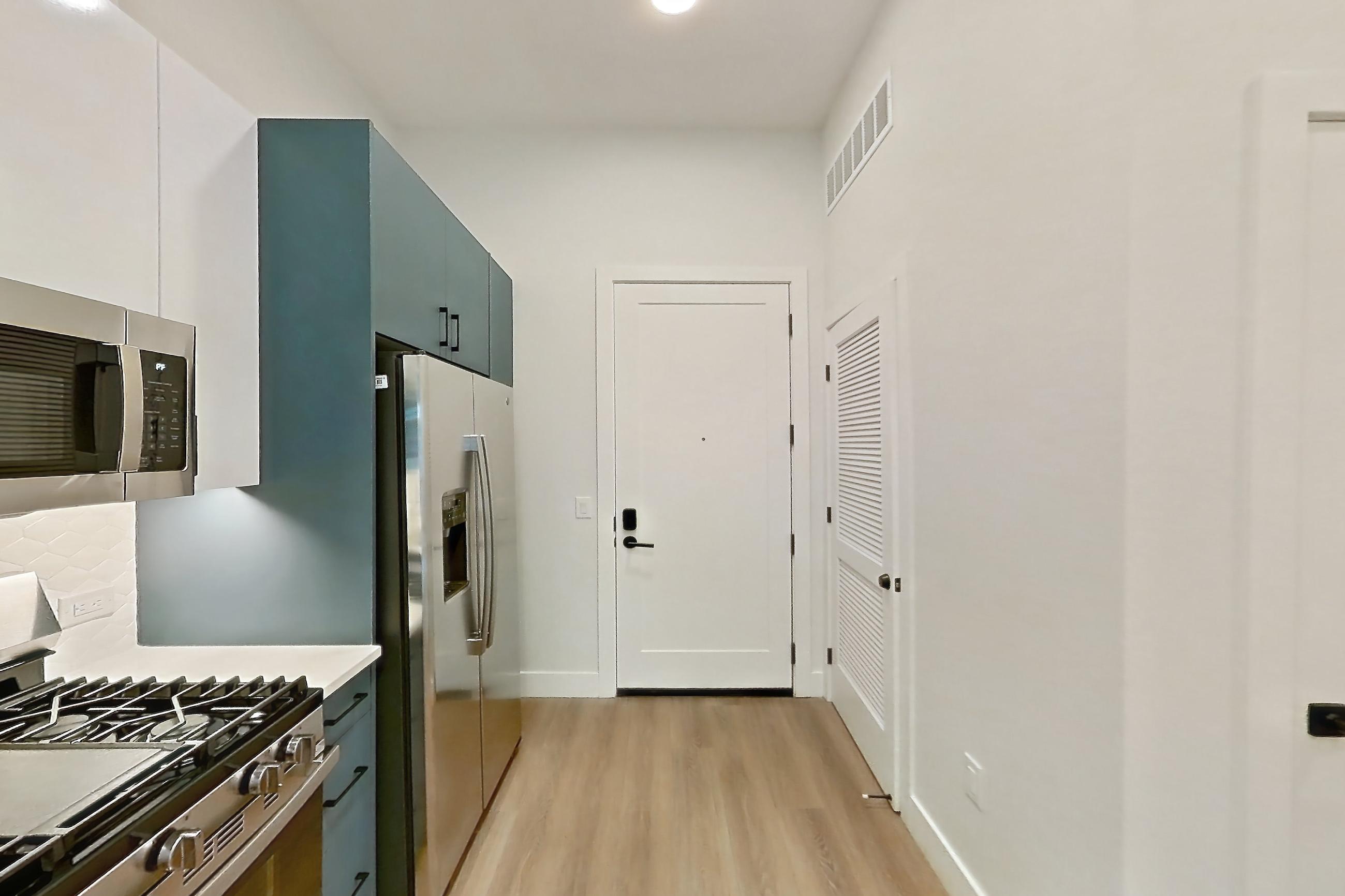Kitchen with dishwasher, gas range, light countertops, light wood-finish flooring, microwave, oven/range, refrigerator, stainless steel appliances, and water & ice dispenser, Apartment 117 at Bria