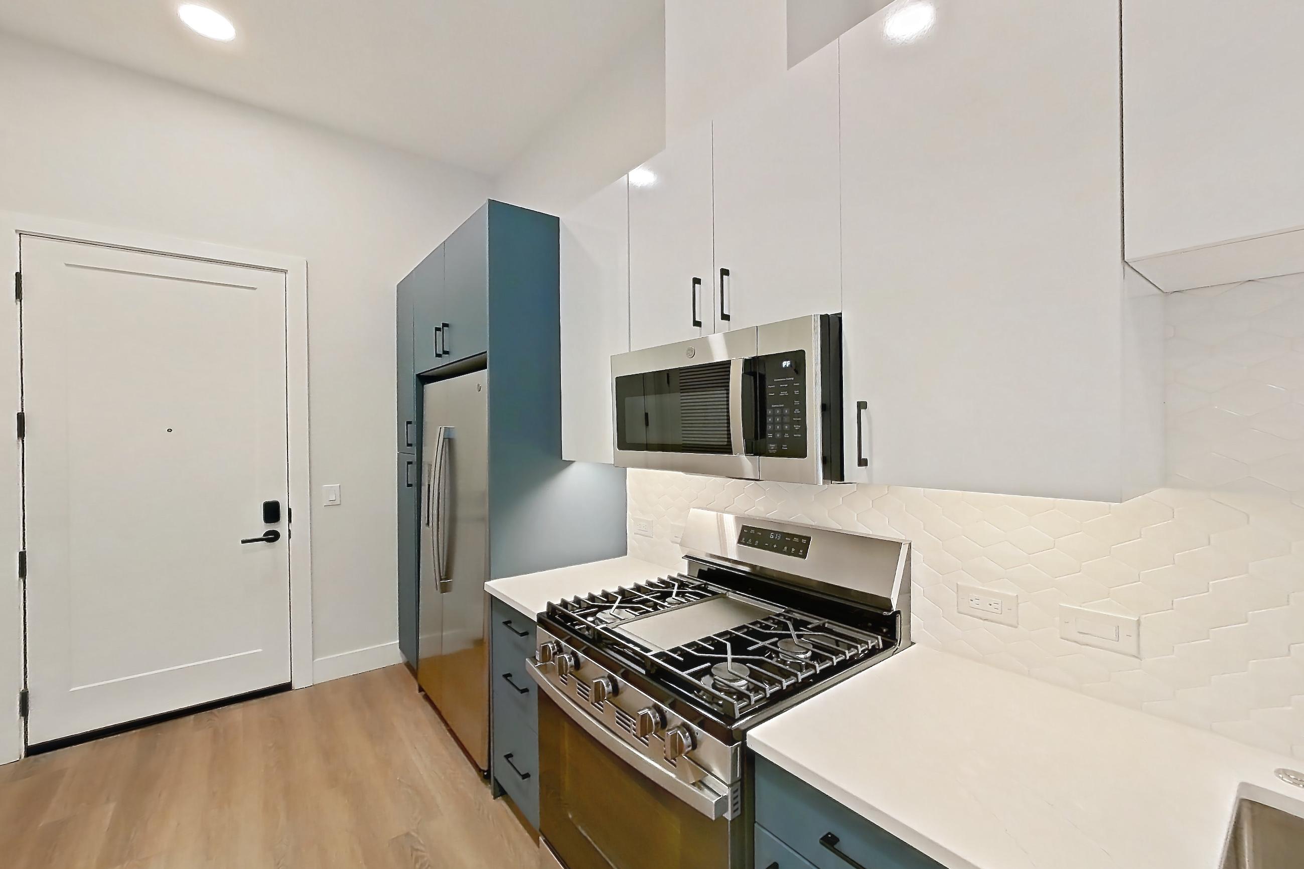 Kitchen with dishwasher, gas range, light countertops, light stone countertops, light wood-finish flooring, microwave, oven/range, and stainless steel appliances, Apartment 119 at Bria