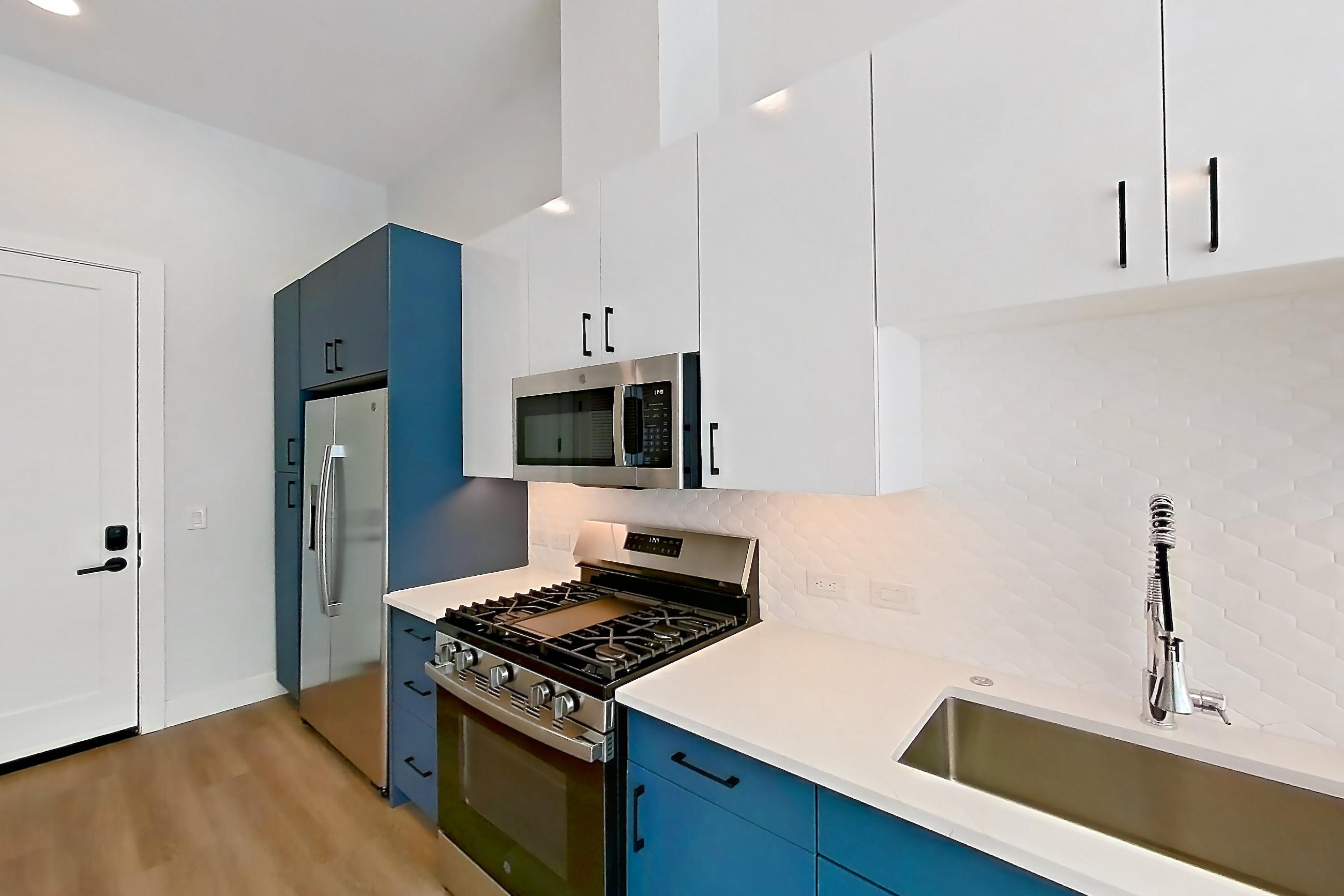 Kitchen with dishwasher, gas range, light countertops, light stone countertops, light wood-finish flooring, microwave, oven/range, refrigerator, and stainless steel appliances, Apartment 132 at Bria