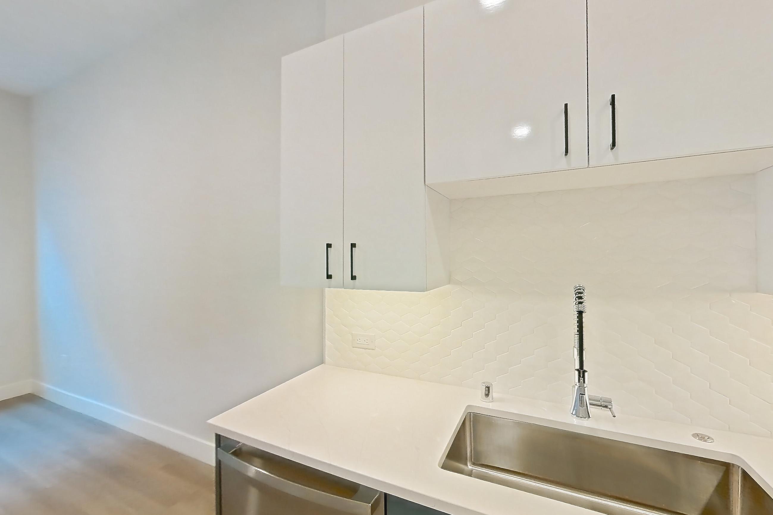 Kitchen with dishwasher, gas range, light countertops, light stone countertops, light wood-finish flooring, microwave, oven/range, refrigerator, stainless steel appliances, and water & ice dispenser, Apartment 115 at Bria