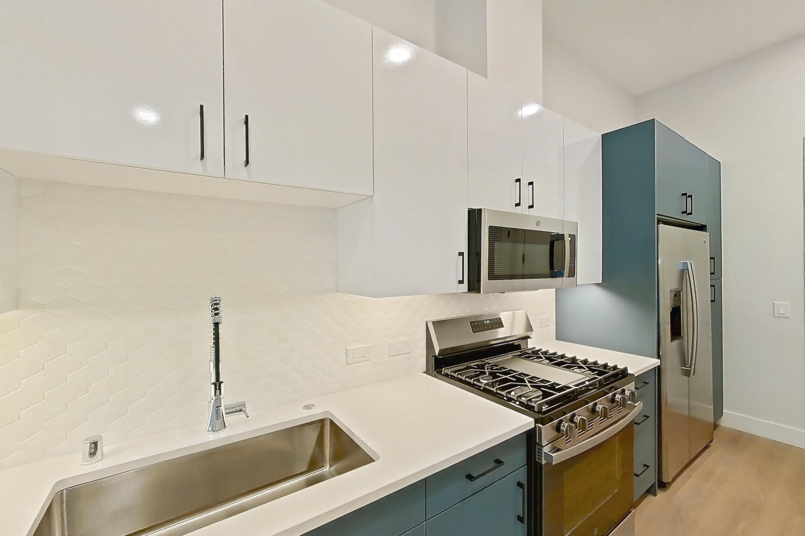 Kitchen with dishwasher, gas range, light countertops, light stone countertops, light wood-finish flooring, microwave, oven/range, refrigerator, stainless steel appliances, and water & ice dispenser, Apartment 115 at Bria