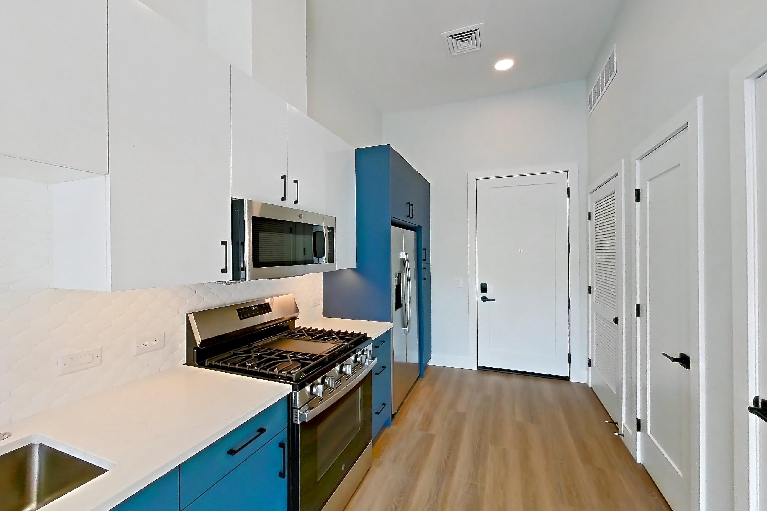 Kitchen with dishwasher, gas range, light countertops, light stone countertops, light wood-finish flooring, microwave, oven/range, refrigerator, and stainless steel appliances, Apartment 569 at Bria