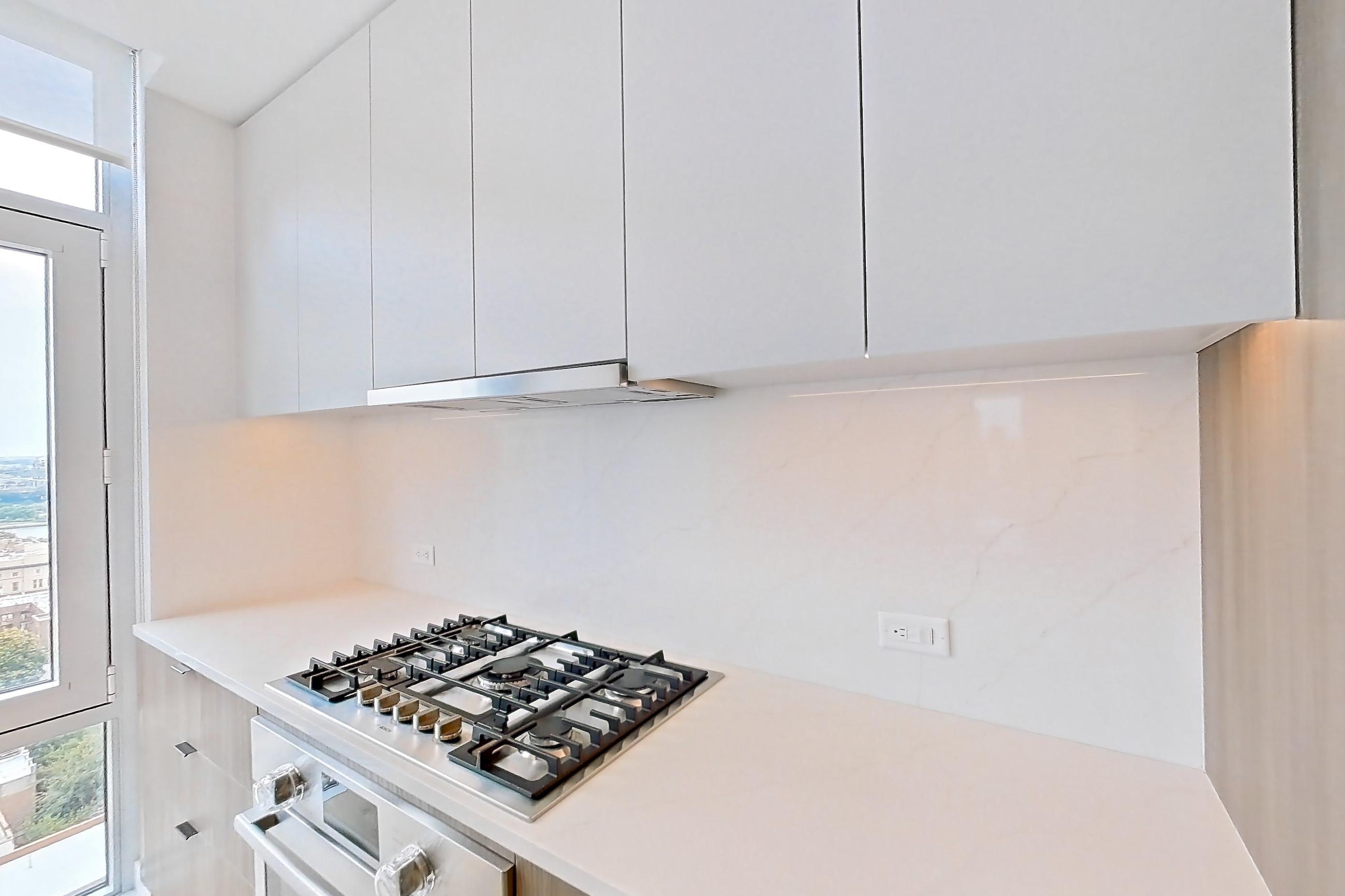Kitchen with cooktop, gas cooktop, light stone countertops, light wood-finish flooring, oven/range, and stainless steel appliances, Apartment 19B at Maison 78