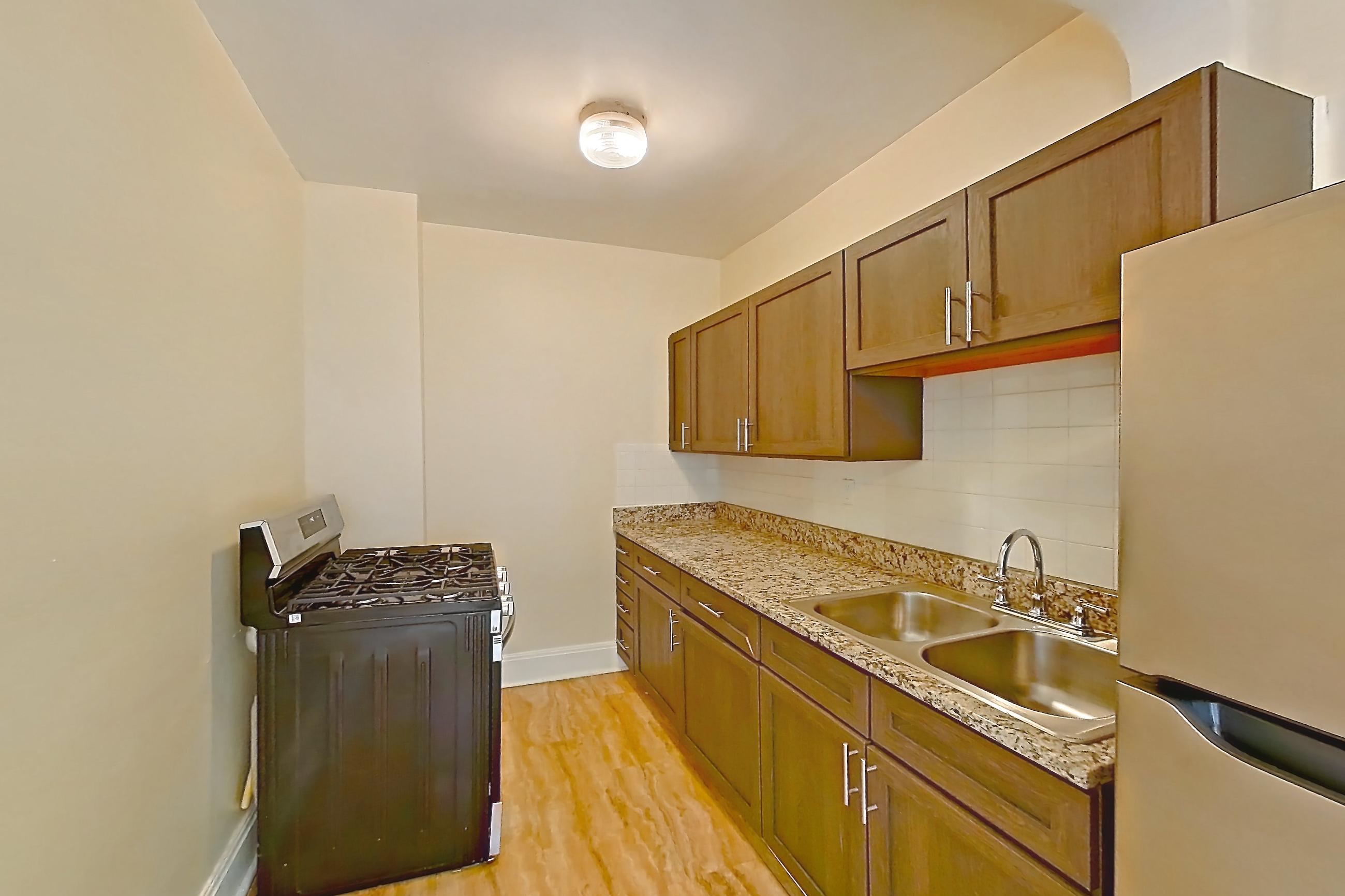 Kitchen with gas range, light countertops, light stone countertops, light wood-finish flooring, oven/range, refrigerator, and stainless steel appliances, Apartment MVI-11 at Mapleview