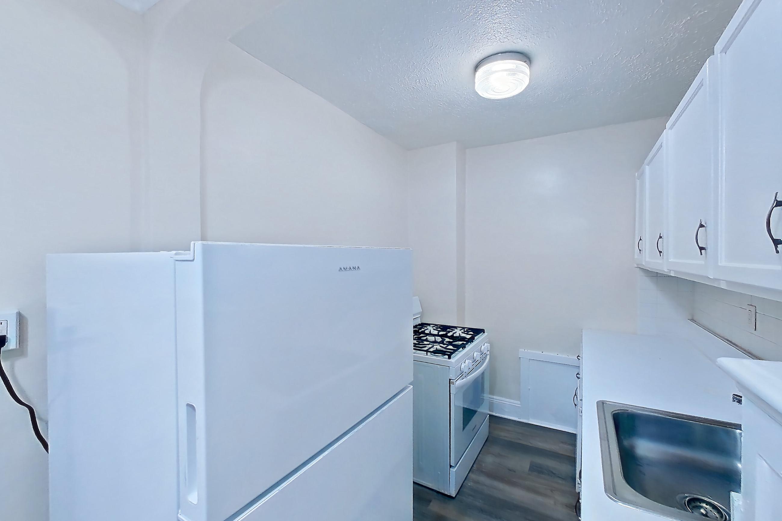 Kitchen with gas range, light countertops, light wood-finish flooring, oven/range, refrigerator, and white appliances, Apartment MVI-03 at Mapleview