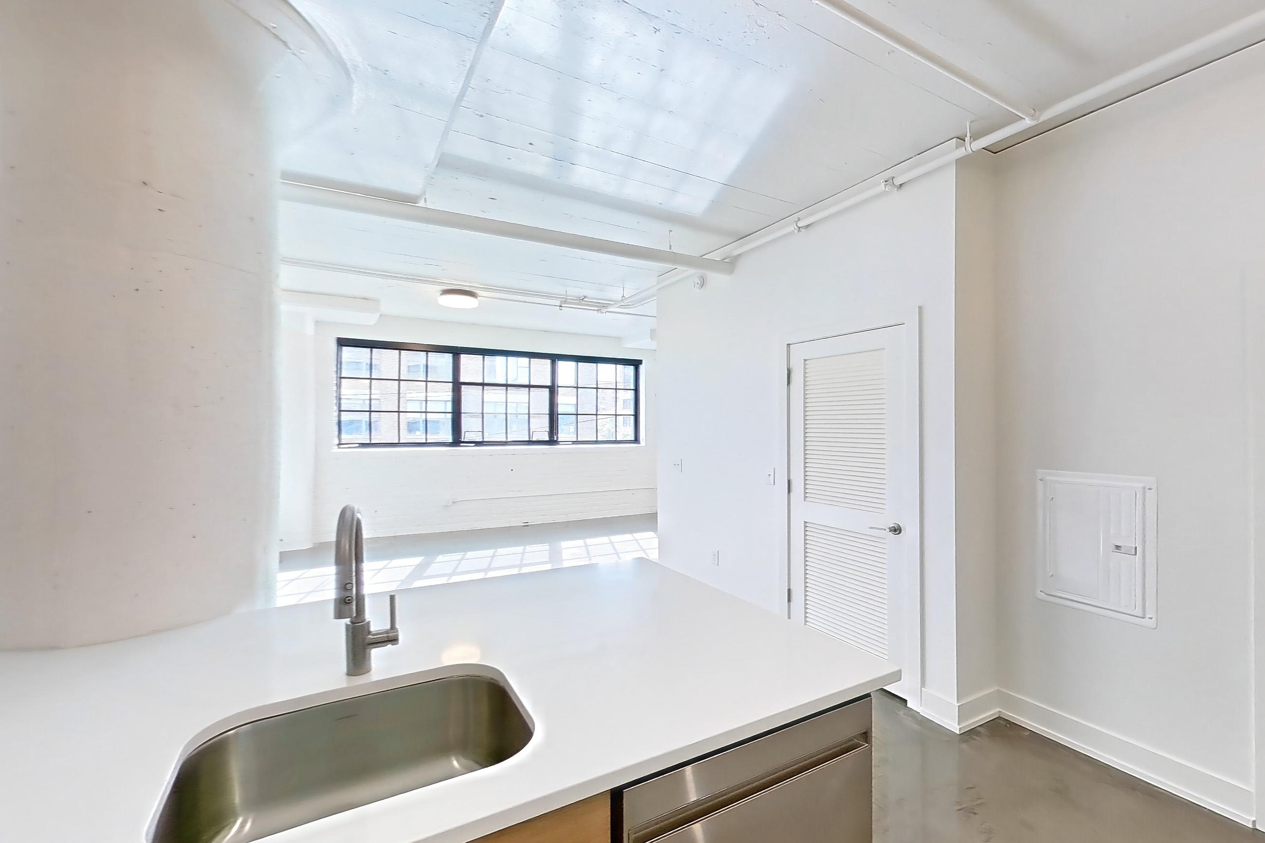 Kitchen with dark concrete flooring, dishwasher, gas range, light countertops, oven/range, refrigerator, and stainless steel appliances, Apartment 246 at The Hall Lofts