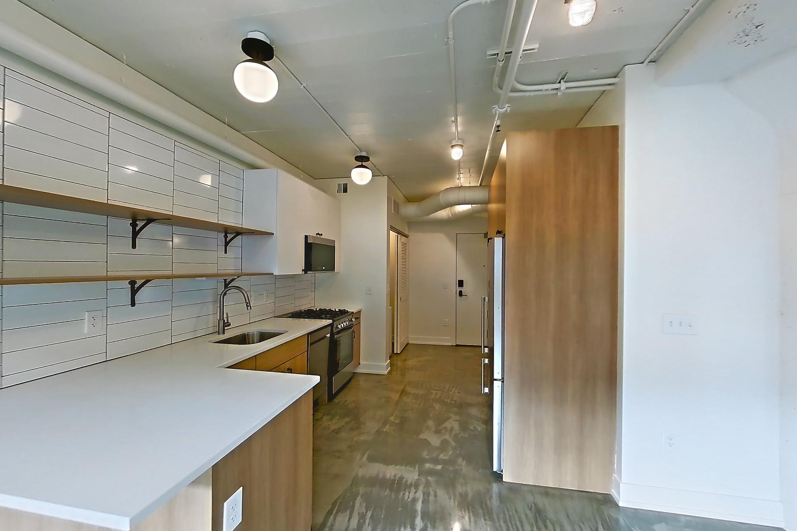 Living room with dark concrete flooring, gas range, light countertops, mini-split AC, oven/range, polished concrete flooring, refrigerator, and stainless steel appliances, Apartment 444 at The Hall Lofts