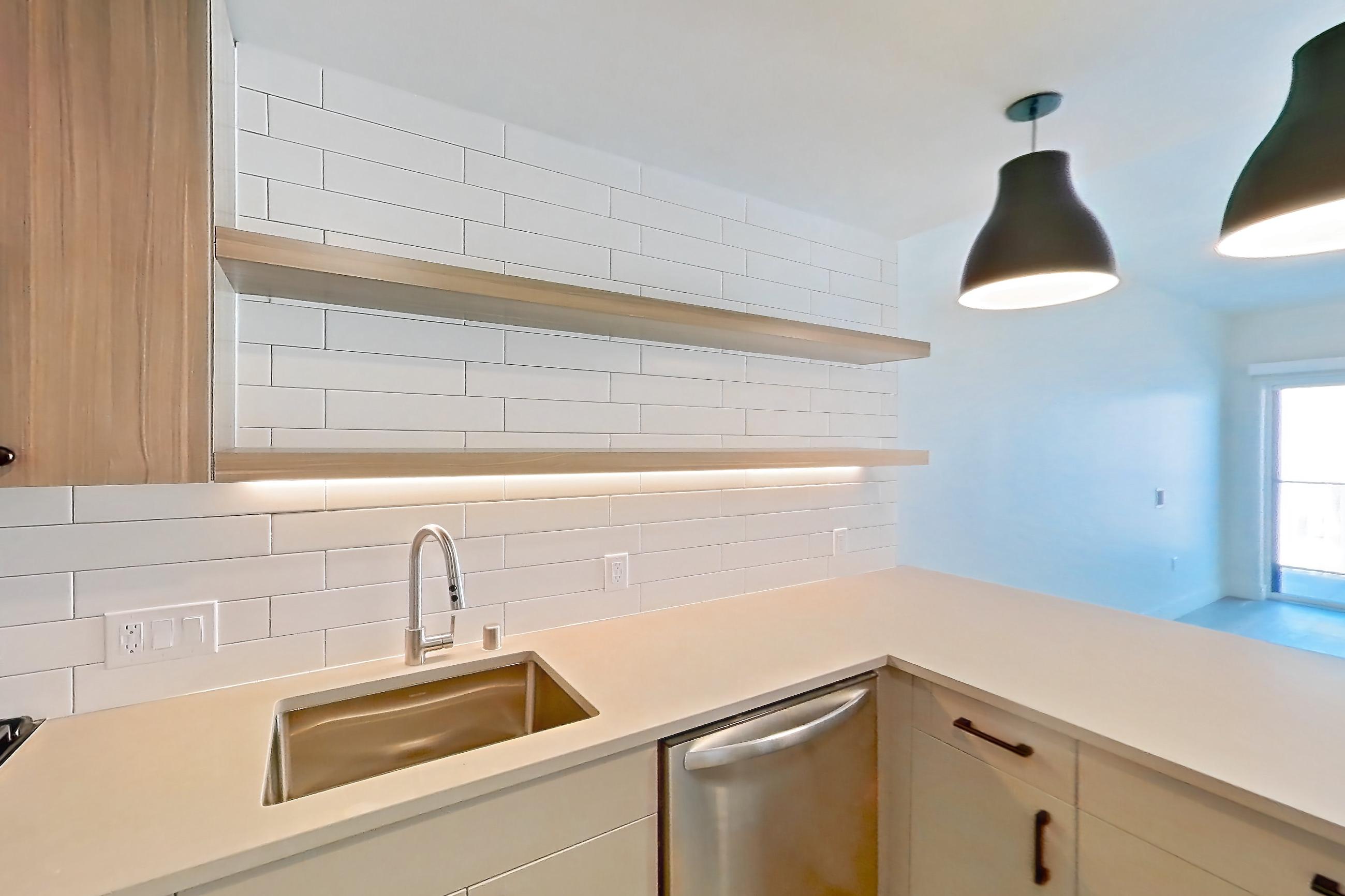 Kitchen with dishwasher, gas range, light countertops, light wood-finish flooring, oven/range, refrigerator, and stainless steel appliances, Apartment 209 at The Myles
