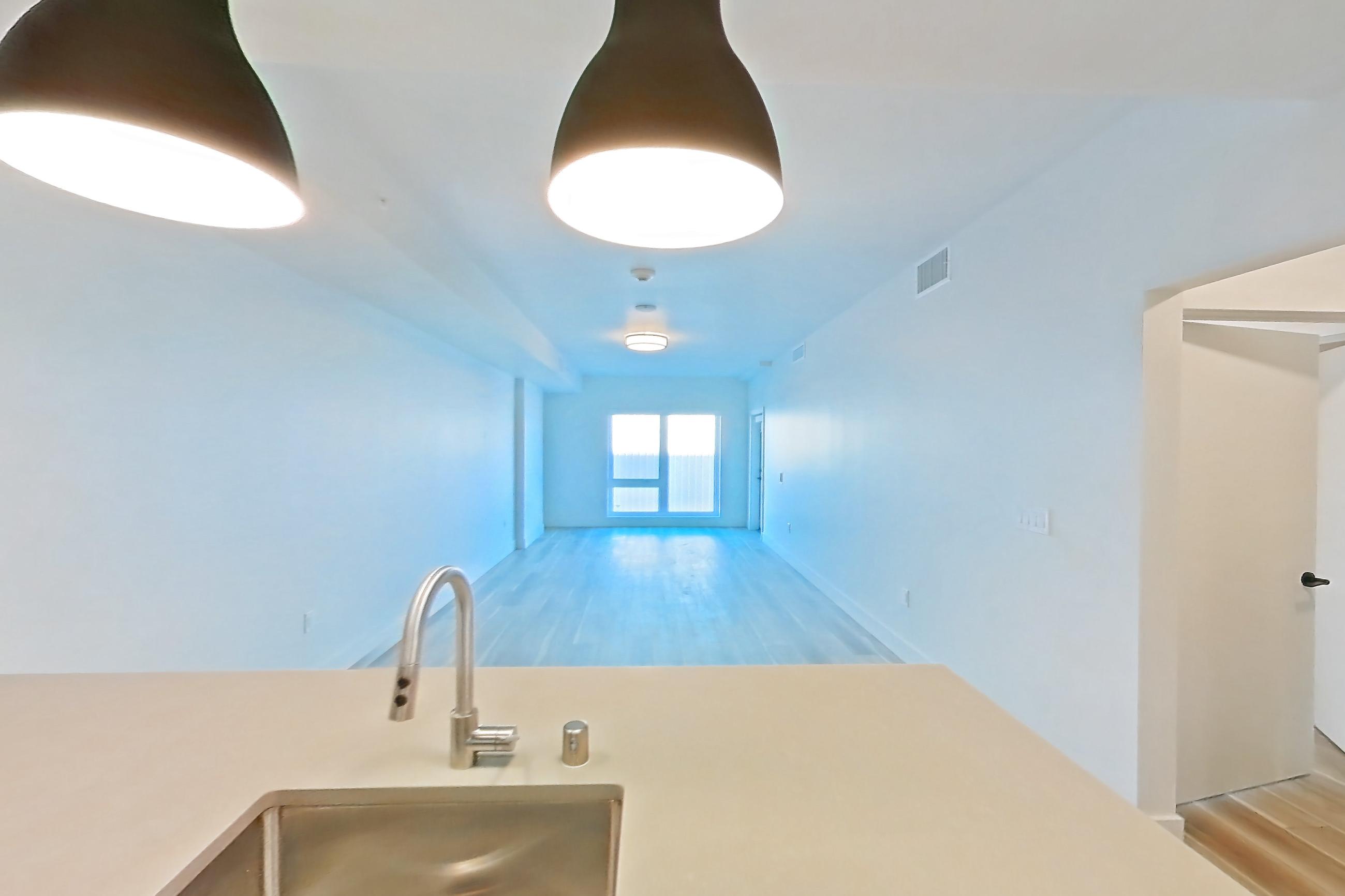 Kitchen with dishwasher, gas range, light countertops, light wood-finish flooring, microwave, oven/range, refrigerator, stainless steel appliances, and wood-look tile flooring, Apartment 214 at The Myles