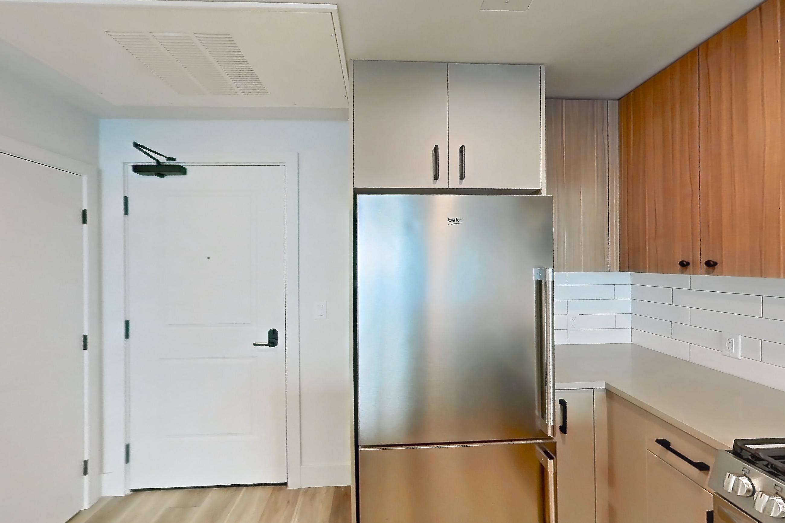 Kitchen with dishwasher, gas range, light countertops, light wood-finish flooring, microwave, oven/range, refrigerator, stainless steel appliances, and wood-look tile flooring, Apartment 214 at The Myles