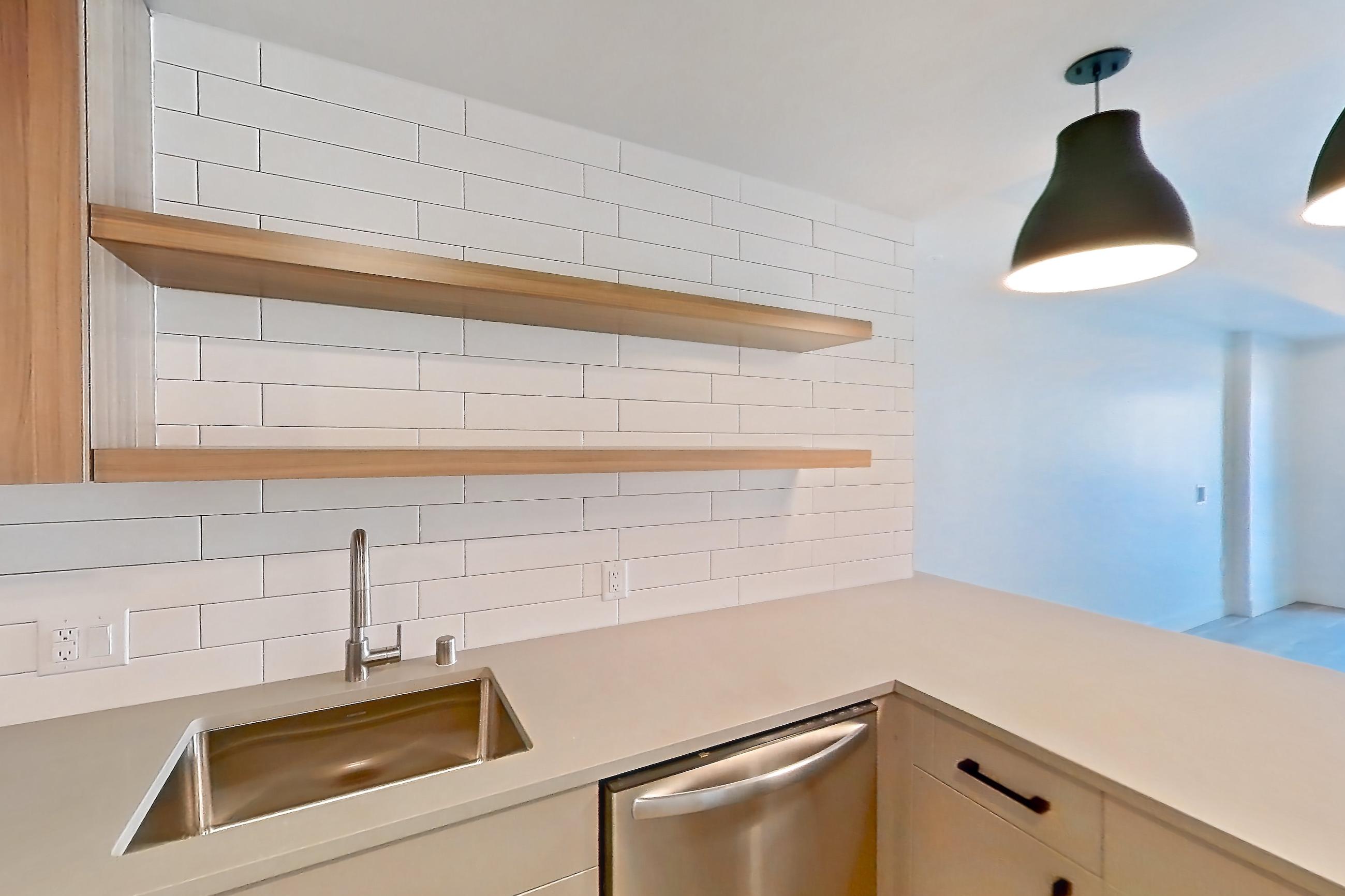 Kitchen with dishwasher, gas range, light countertops, light wood-finish flooring, microwave, oven/range, refrigerator, and stainless steel appliances, Apartment 216 at The Myles