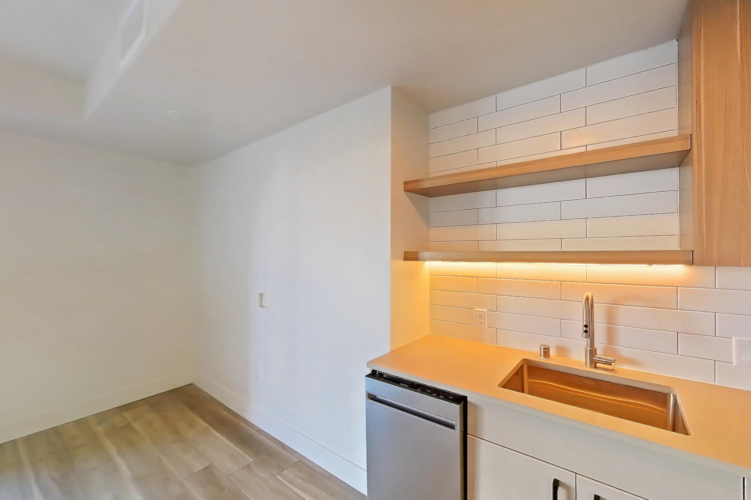Kitchen with dishwasher, gas range, light countertops, light wood-finish flooring, oven/range, refrigerator, and stainless steel appliances, Apartment 220 at The Myles