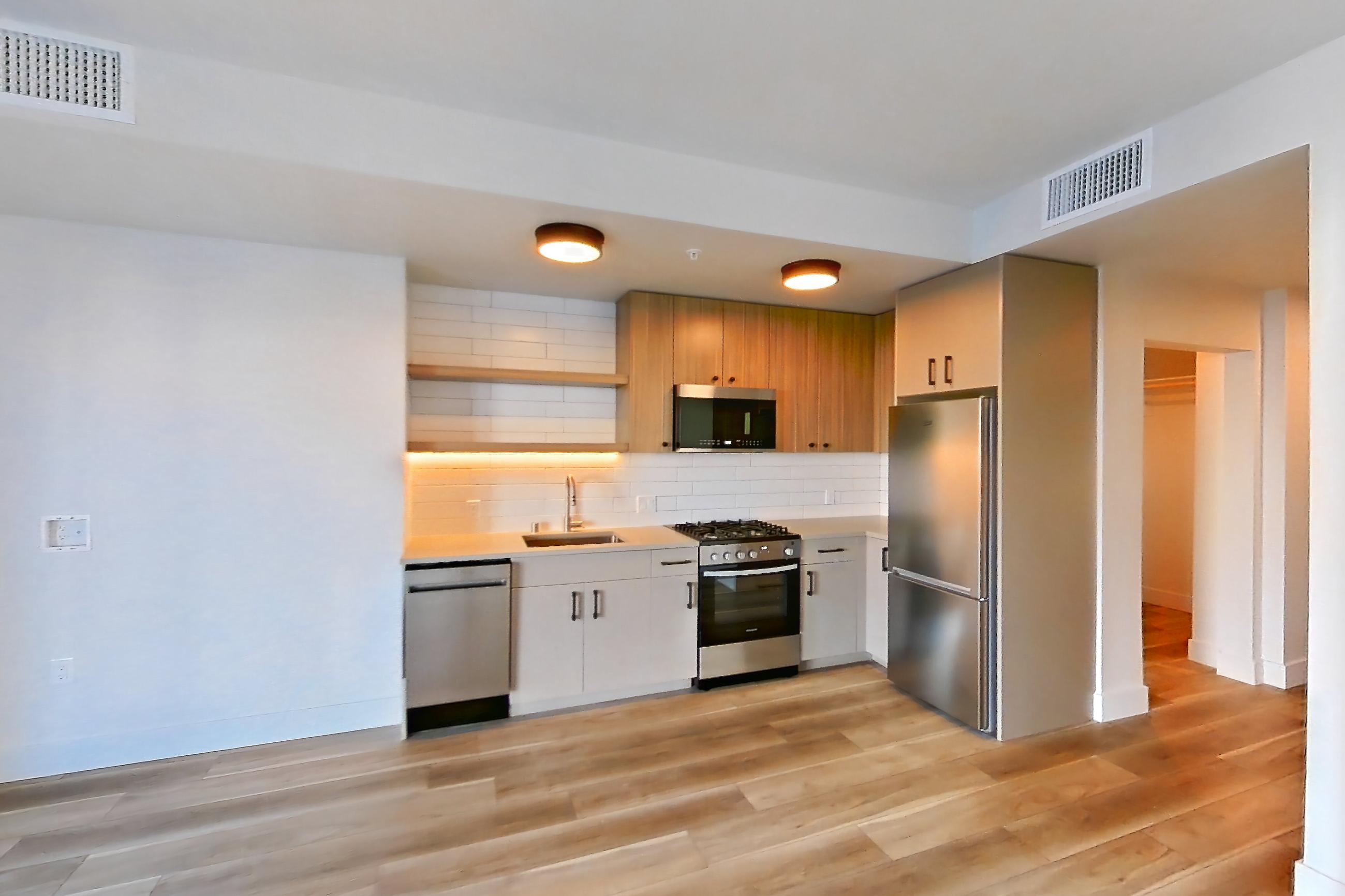 Living space with dishwasher, gas range, light countertops, light wood-finish flooring, oven/range, and stainless steel appliances, Apartment 220 at The Myles