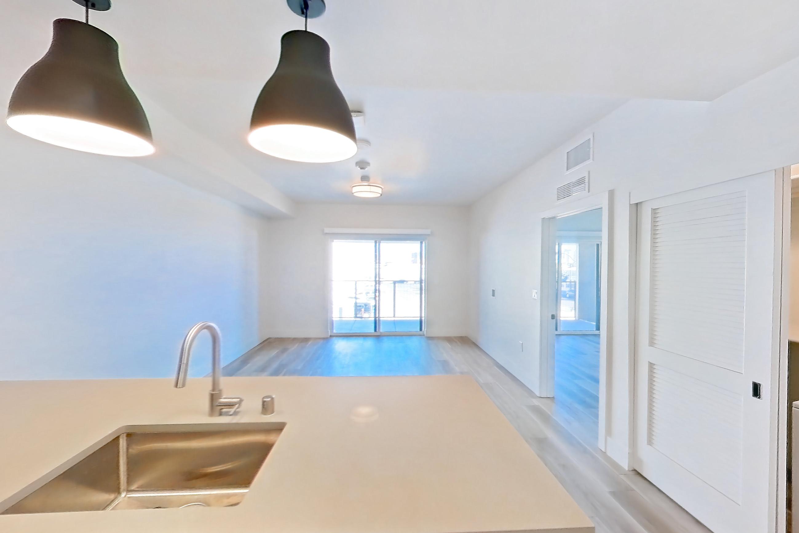Kitchen with dishwasher, gas range, light countertops, light wood-finish flooring, oven/range, refrigerator, and stainless steel appliances, Apartment 223 at The Myles