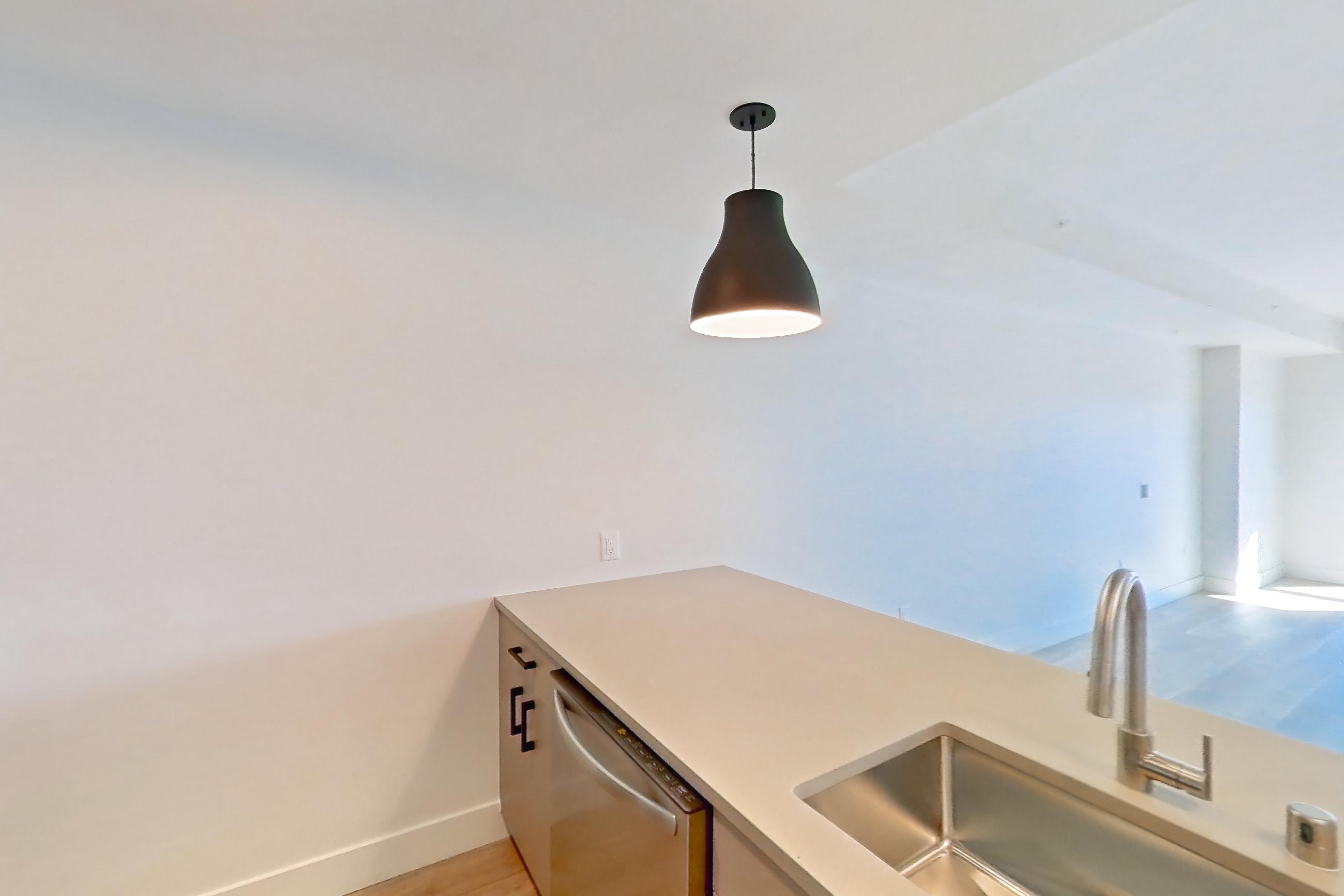 Kitchen with dishwasher, gas range, light countertops, light wood-finish flooring, microwave, oven/range, refrigerator, and stainless steel appliances, Apartment 230 at The Myles