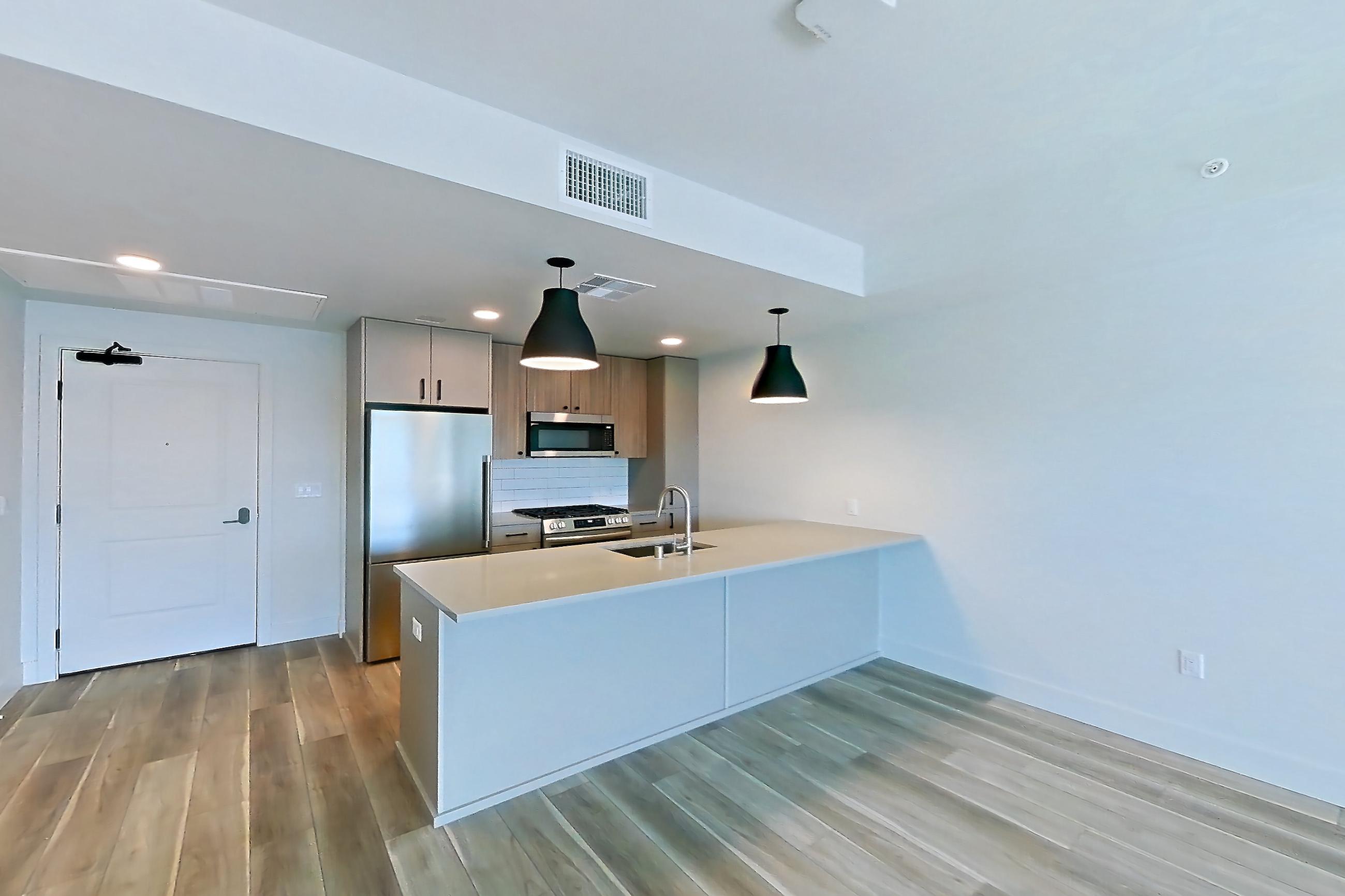 Living room with gas range, light countertops, light wood-finish flooring, oven/range, and stainless steel appliances, Apartment 230 at The Myles