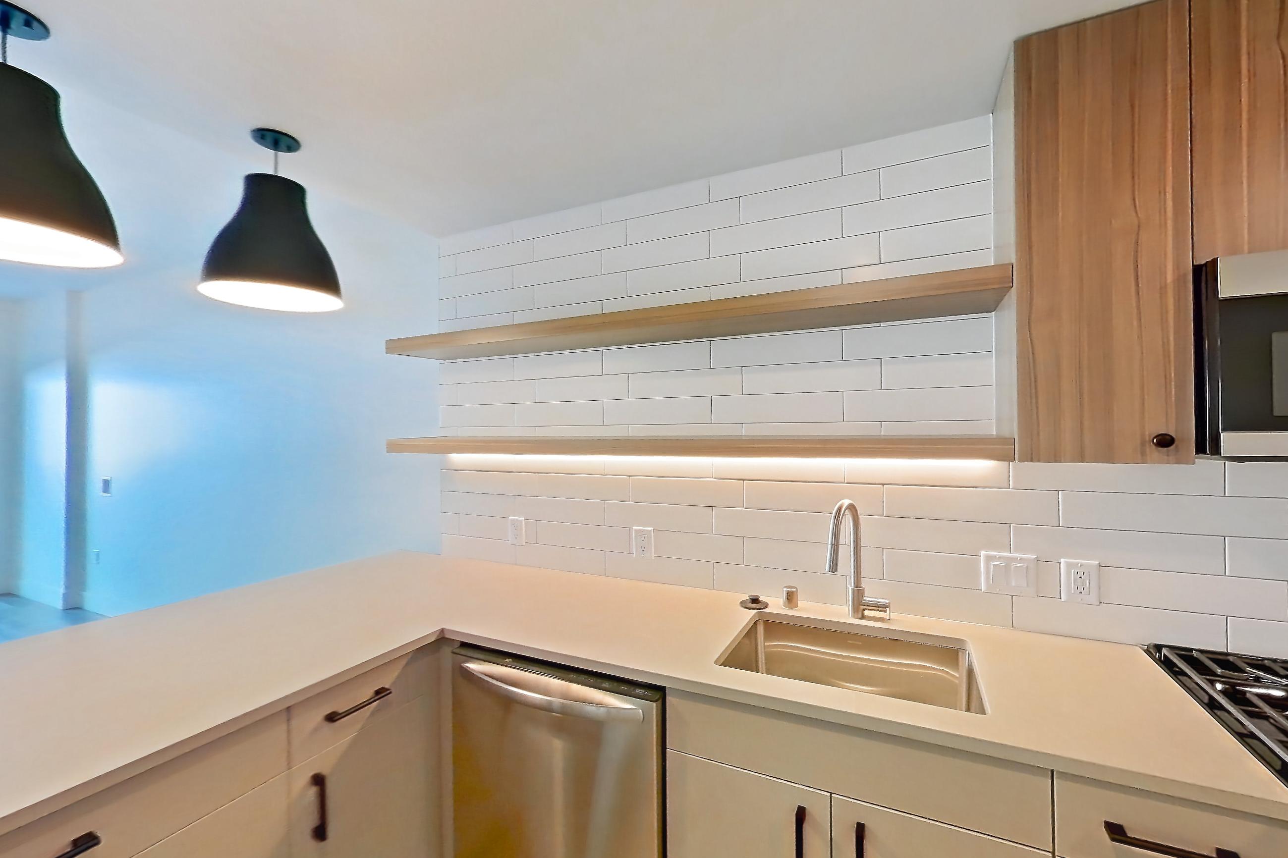 Kitchen with dishwasher, gas range, light countertops, light wood-finish flooring, microwave, oven/range, refrigerator, and stainless steel appliances, Apartment 234 at The Myles