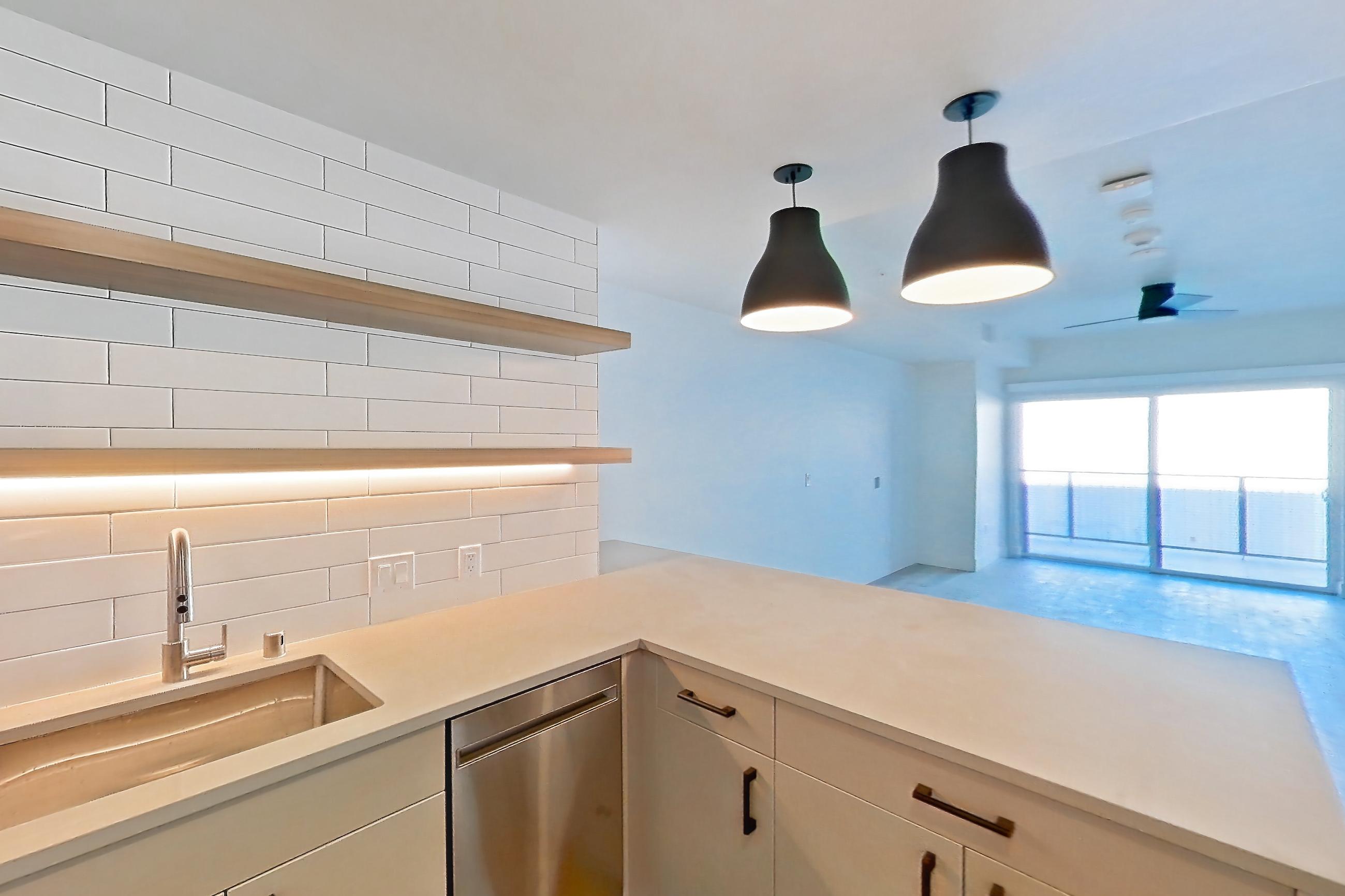 Kitchen with dishwasher, gas range, light countertops, light stone countertops, light wood-finish flooring, oven/range, refrigerator, and stainless steel appliances, Apartment 235 at The Myles