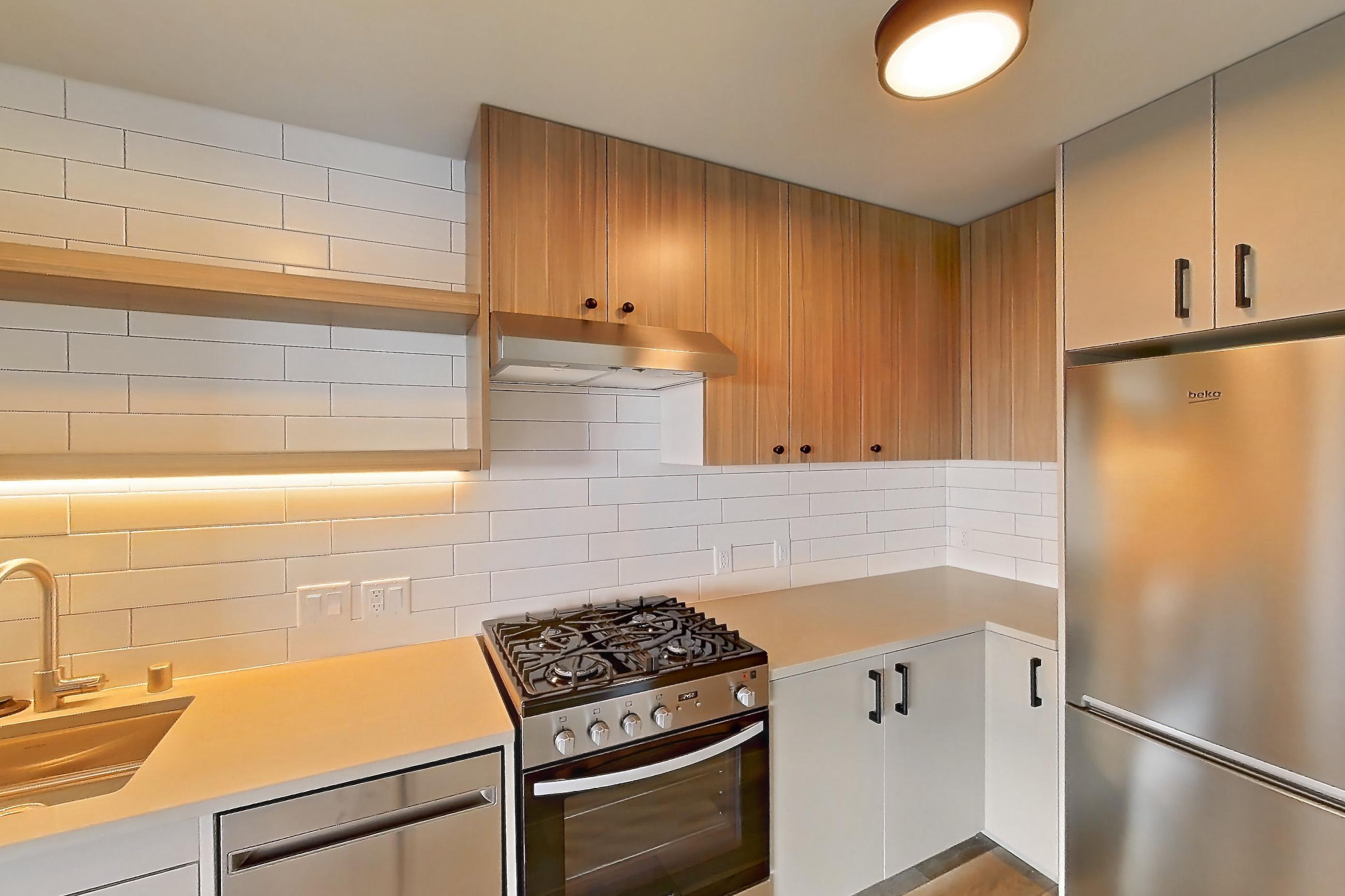 Kitchen with dishwasher, gas range, light countertops, light wood-finish flooring, oven/range, refrigerator, and stainless steel appliances, Apartment 243 at The Myles