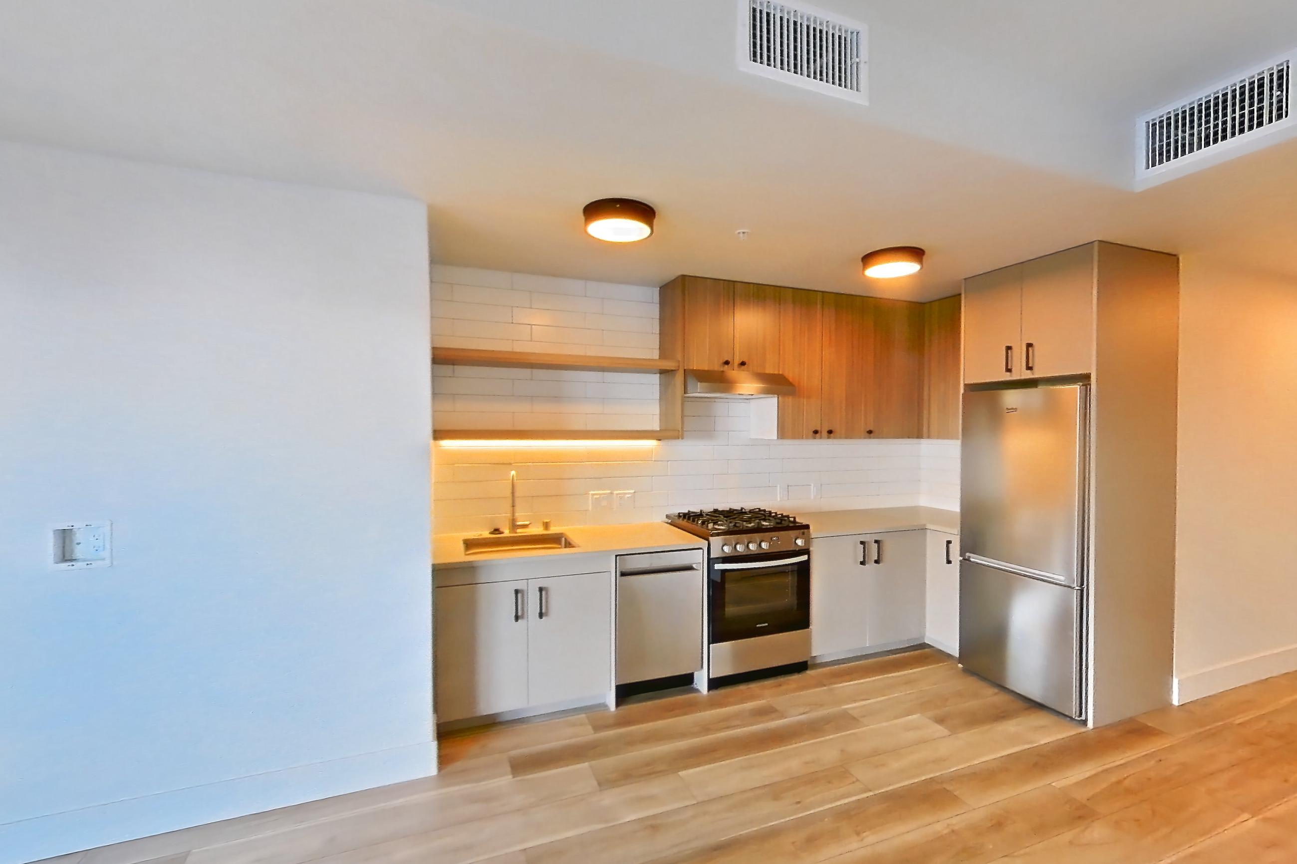Living space with dishwasher, gas range, light countertops, light wood-finish flooring, oven/range, and stainless steel appliances, Apartment 243 at The Myles