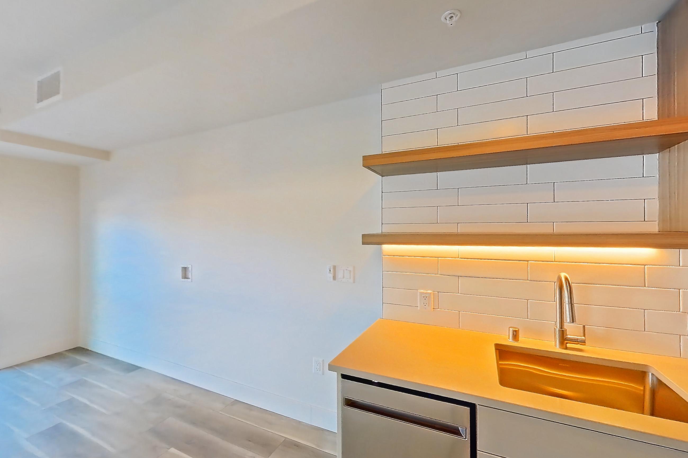 Kitchen with dishwasher, gas range, light countertops, light wood-finish flooring, oven/range, refrigerator, and stainless steel appliances, Apartment 253 at The Myles