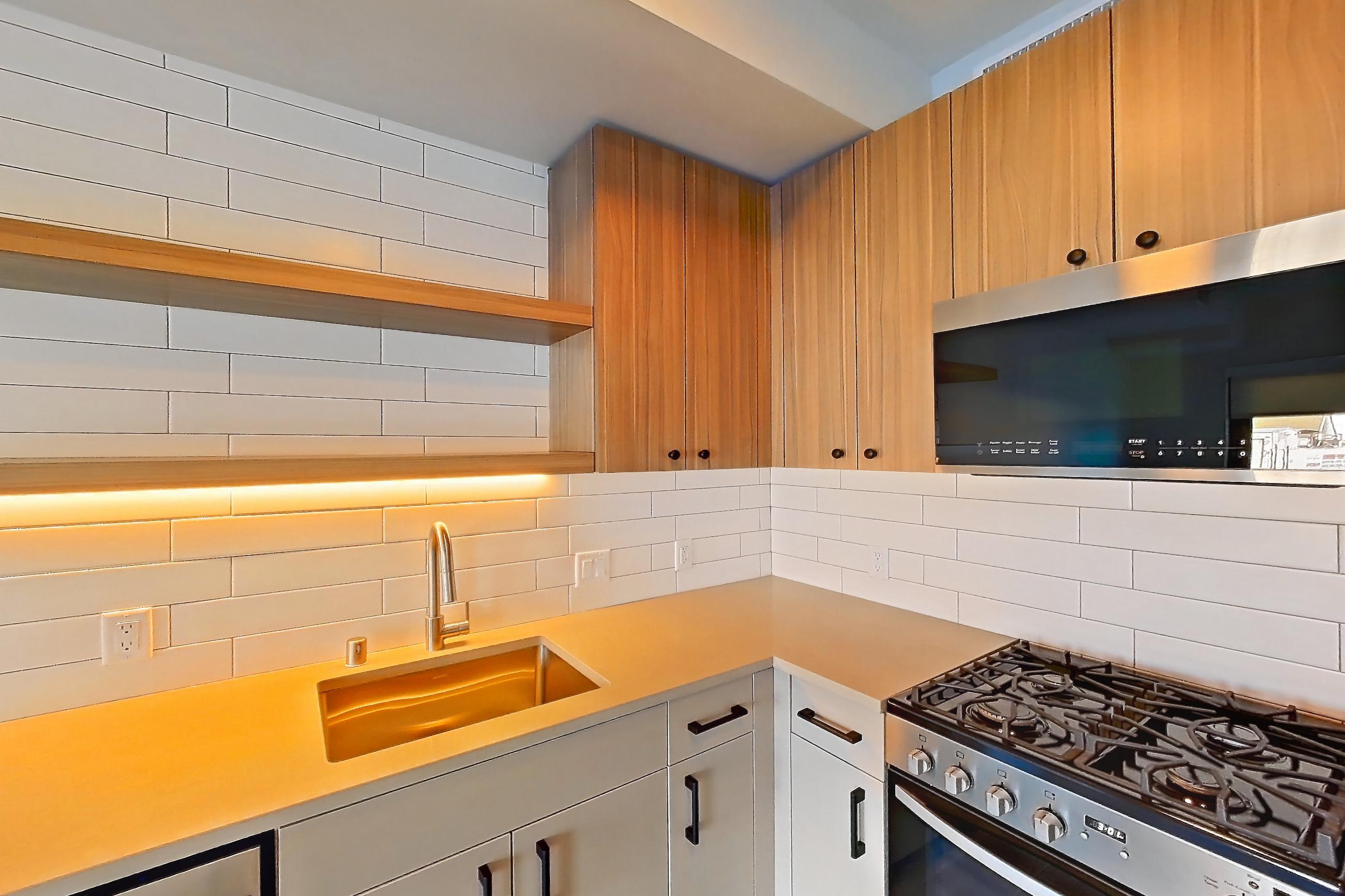Kitchen with dishwasher, gas range, light countertops, light wood-finish flooring, oven/range, refrigerator, and stainless steel appliances, Apartment 253 at The Myles