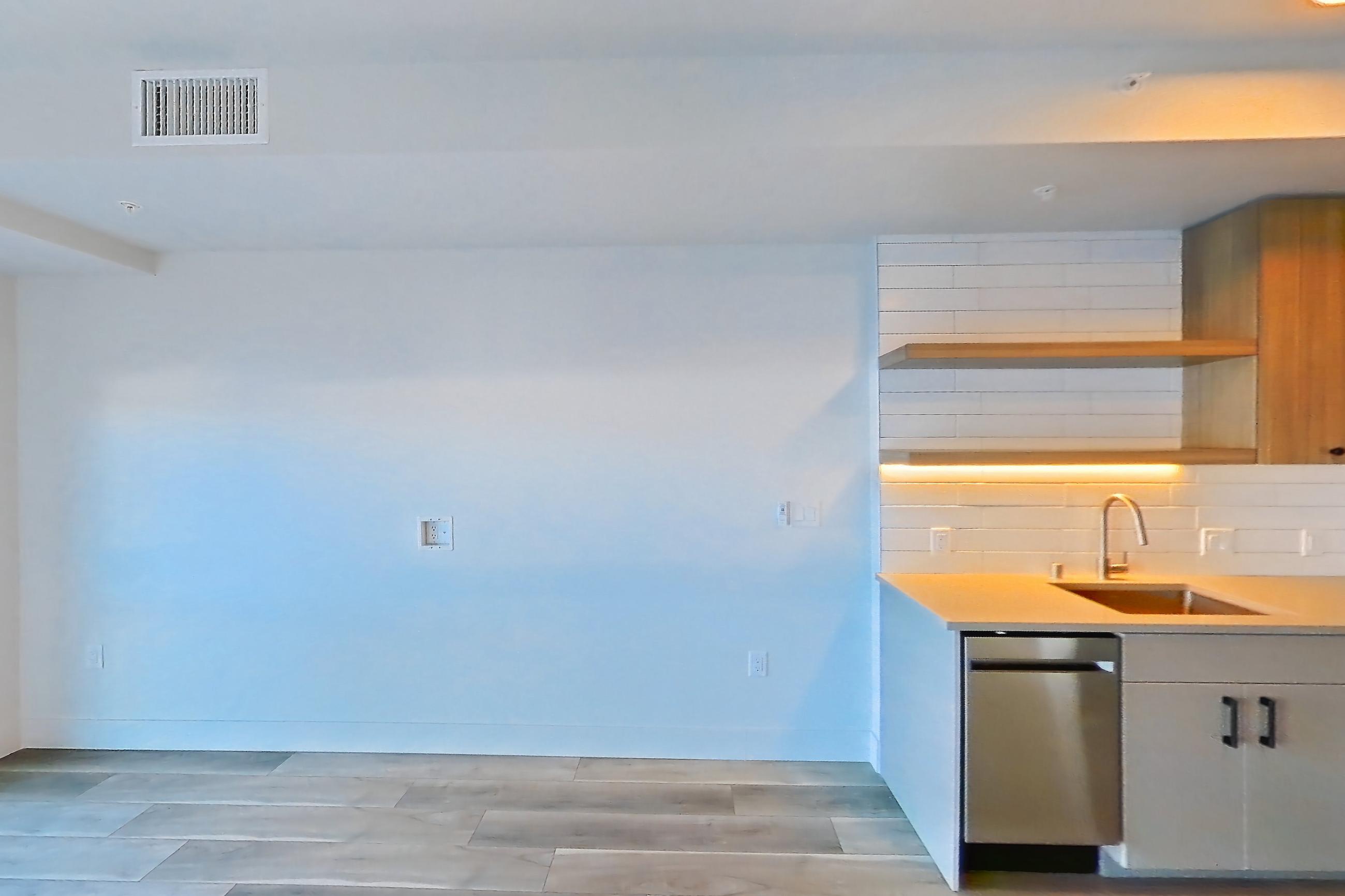 Living space with dishwasher, gas range, light countertops, light wood-finish flooring, oven/range, refrigerator, and stainless steel appliances, Apartment 253 at The Myles