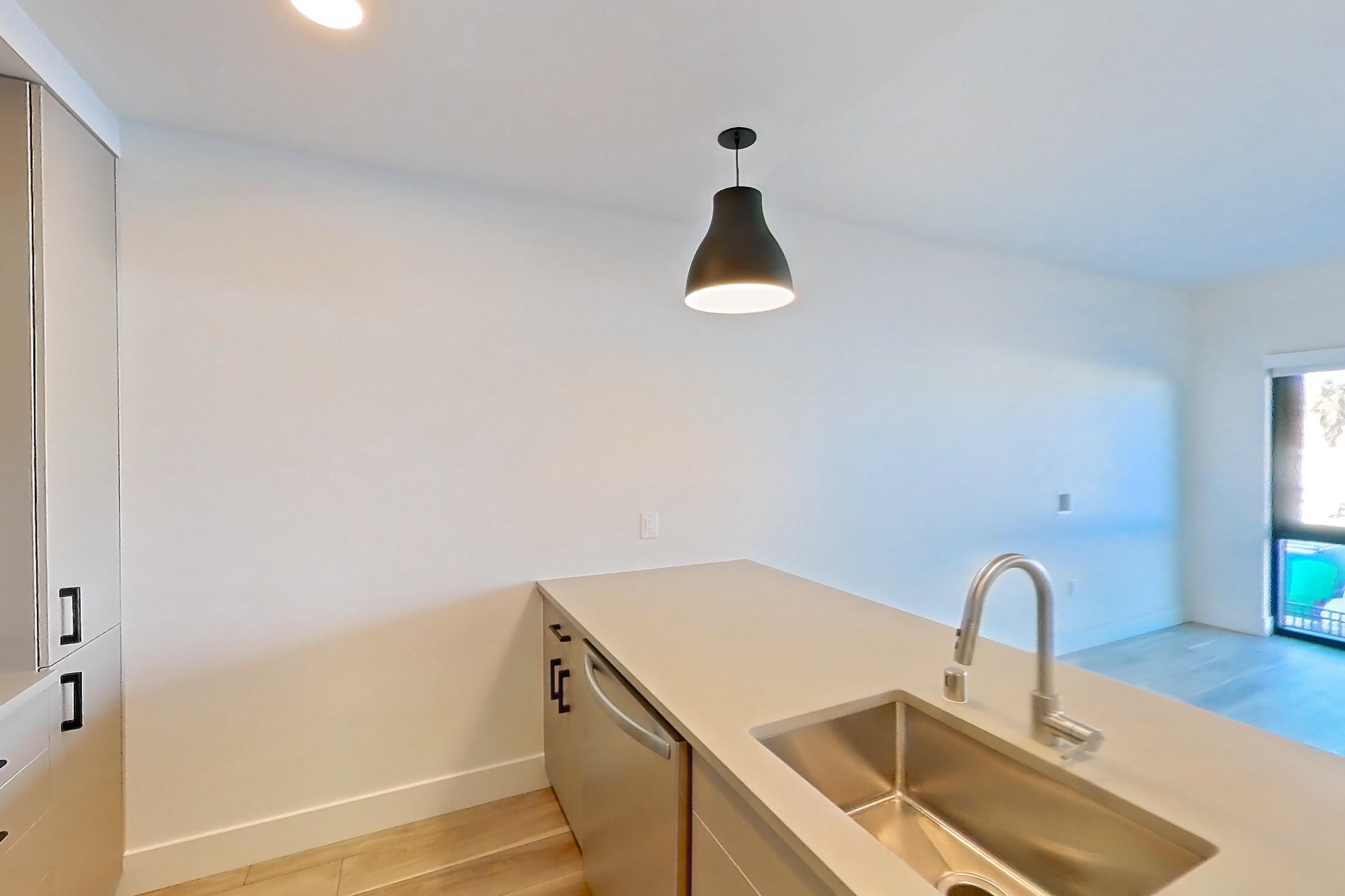 Kitchen with dishwasher, gas range, light countertops, light wood-finish flooring, oven/range, refrigerator, and stainless steel appliances, Apartment 255 at The Myles