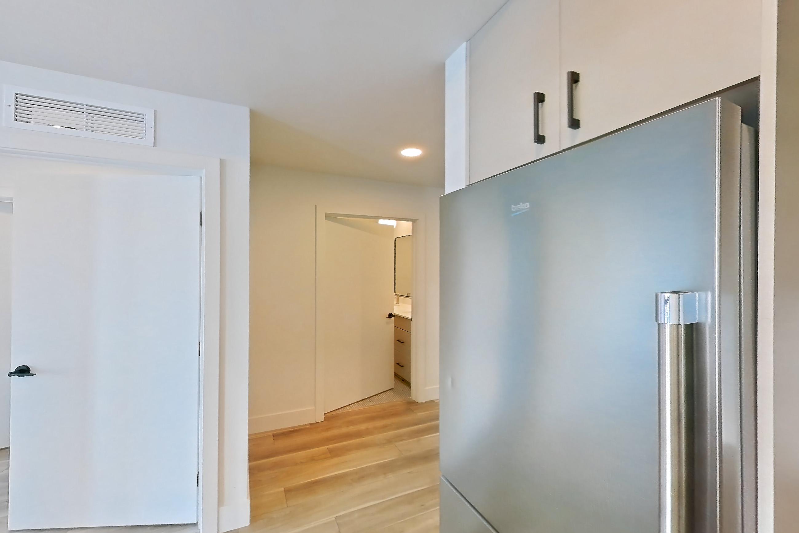 Kitchen with dishwasher, gas range, light countertops, light wood-finish flooring, oven/range, refrigerator, and stainless steel appliances, Apartment 255 at The Myles