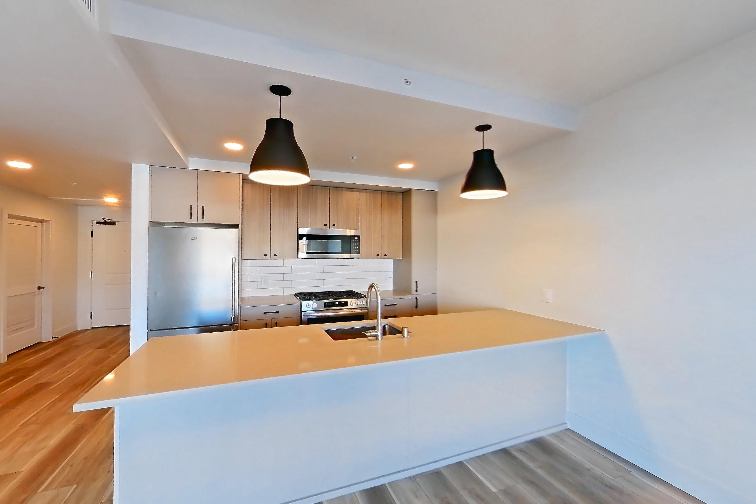 Living room with gas range, light countertops, light wood-finish flooring, oven/range, and stainless steel appliances, Apartment 255 at The Myles