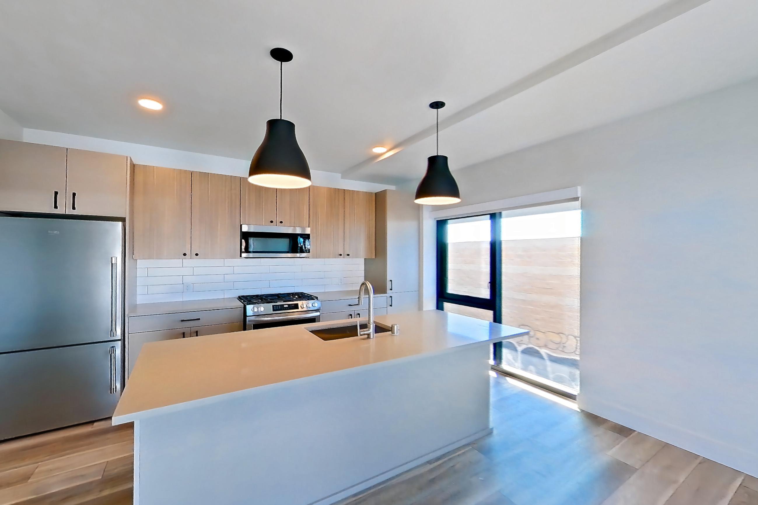 Living room with gas range, light countertops, light wood-finish flooring, oven/range, and stainless steel appliances, Apartment 258 at The Myles