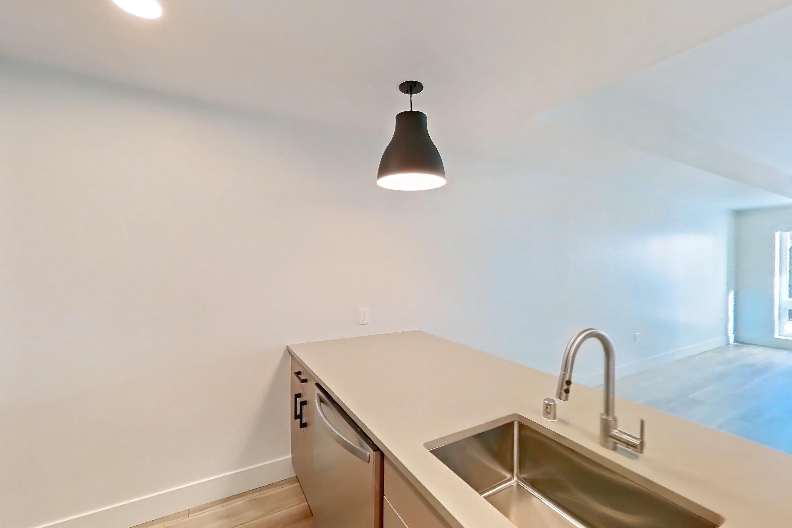 Kitchen with dishwasher, gas range, light countertops, light wood-finish flooring, microwave, oven/range, refrigerator, and stainless steel appliances, Apartment 311 at The Myles