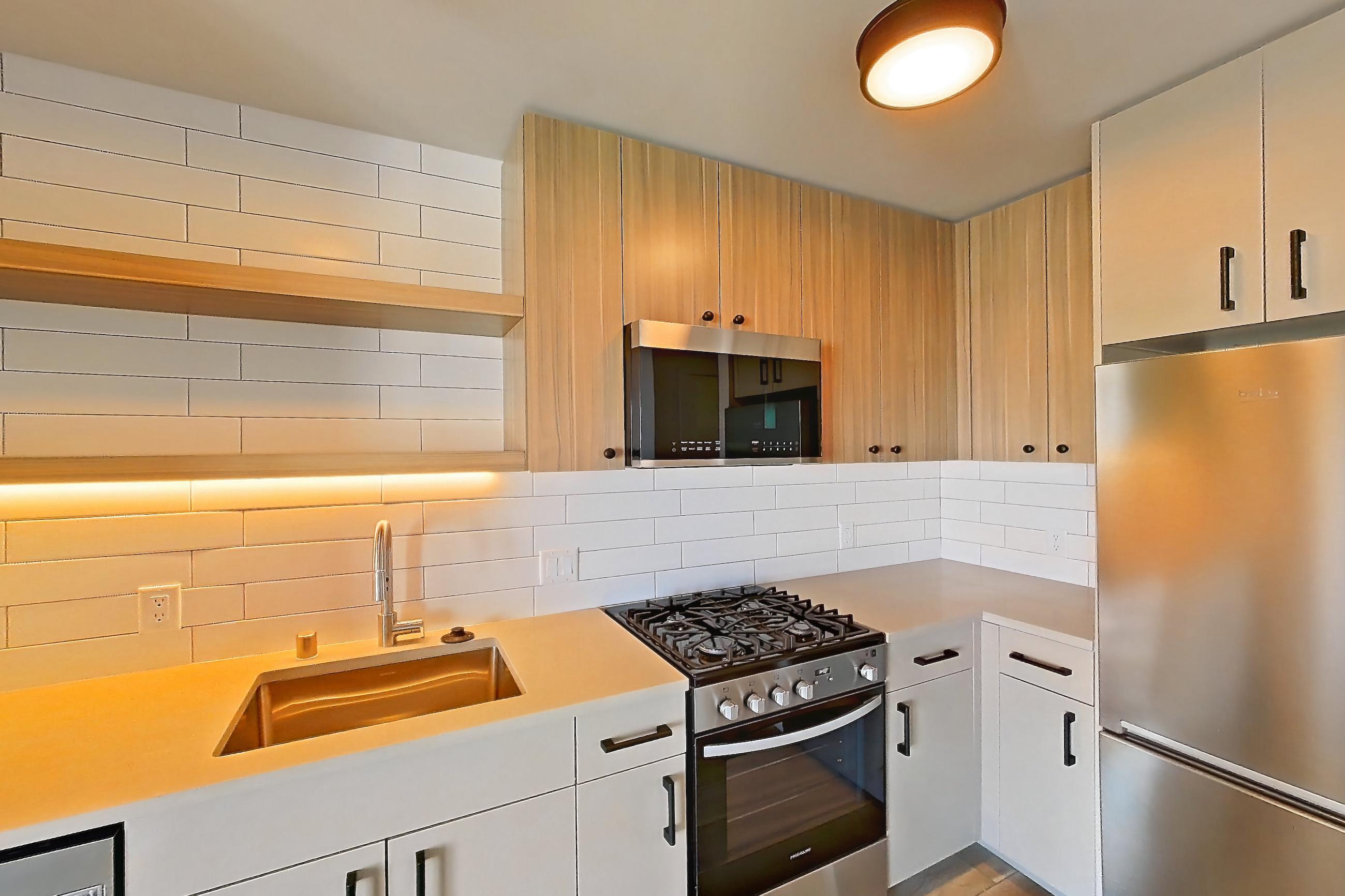 Kitchen with gas range, light countertops, light wood-finish flooring, oven/range, refrigerator, and stainless steel appliances, Apartment 320 at The Myles