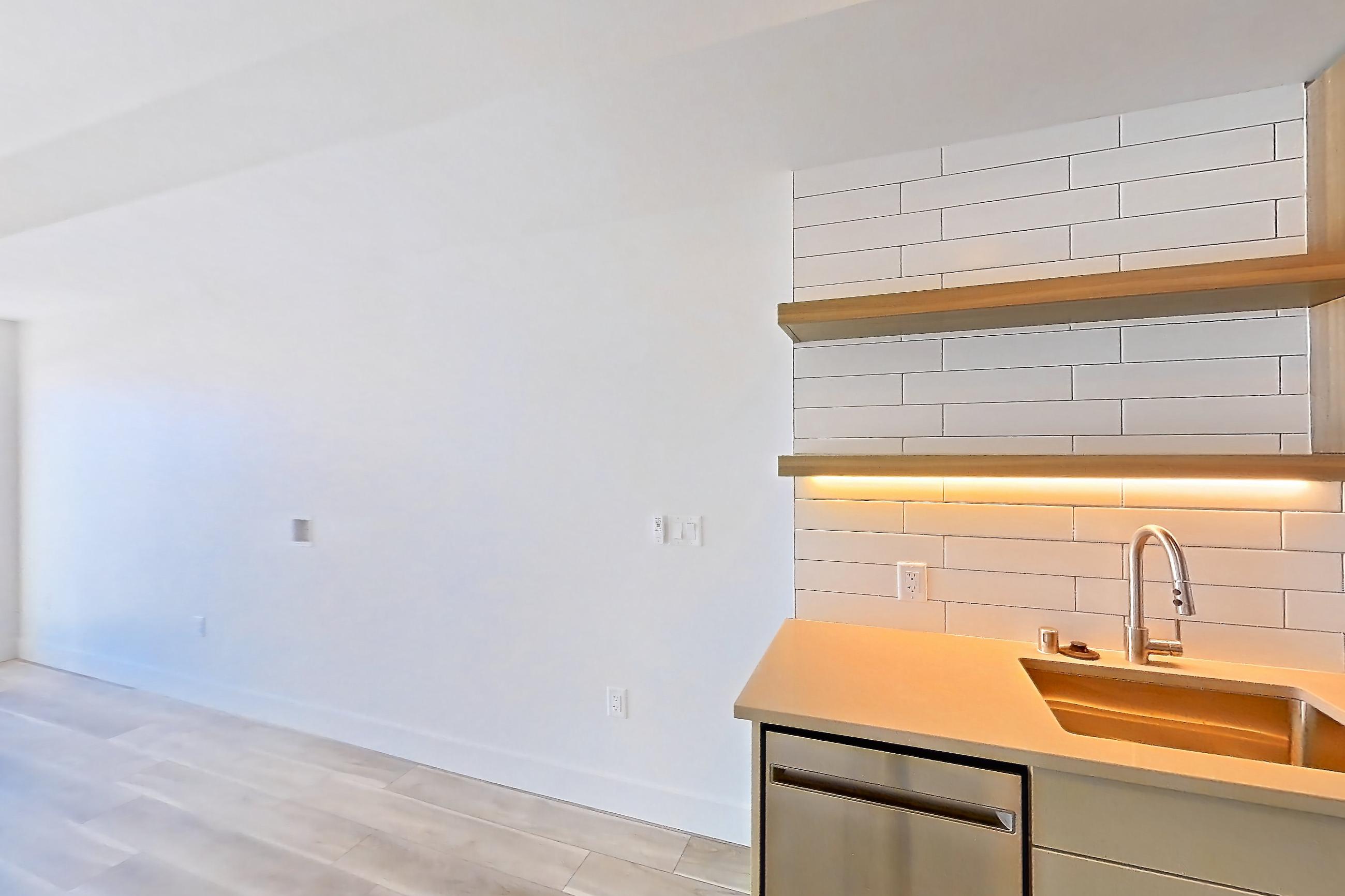 Kitchen with dishwasher, gas range, light countertops, light wood-finish flooring, oven/range, refrigerator, and stainless steel appliances, Apartment 326 at The Myles