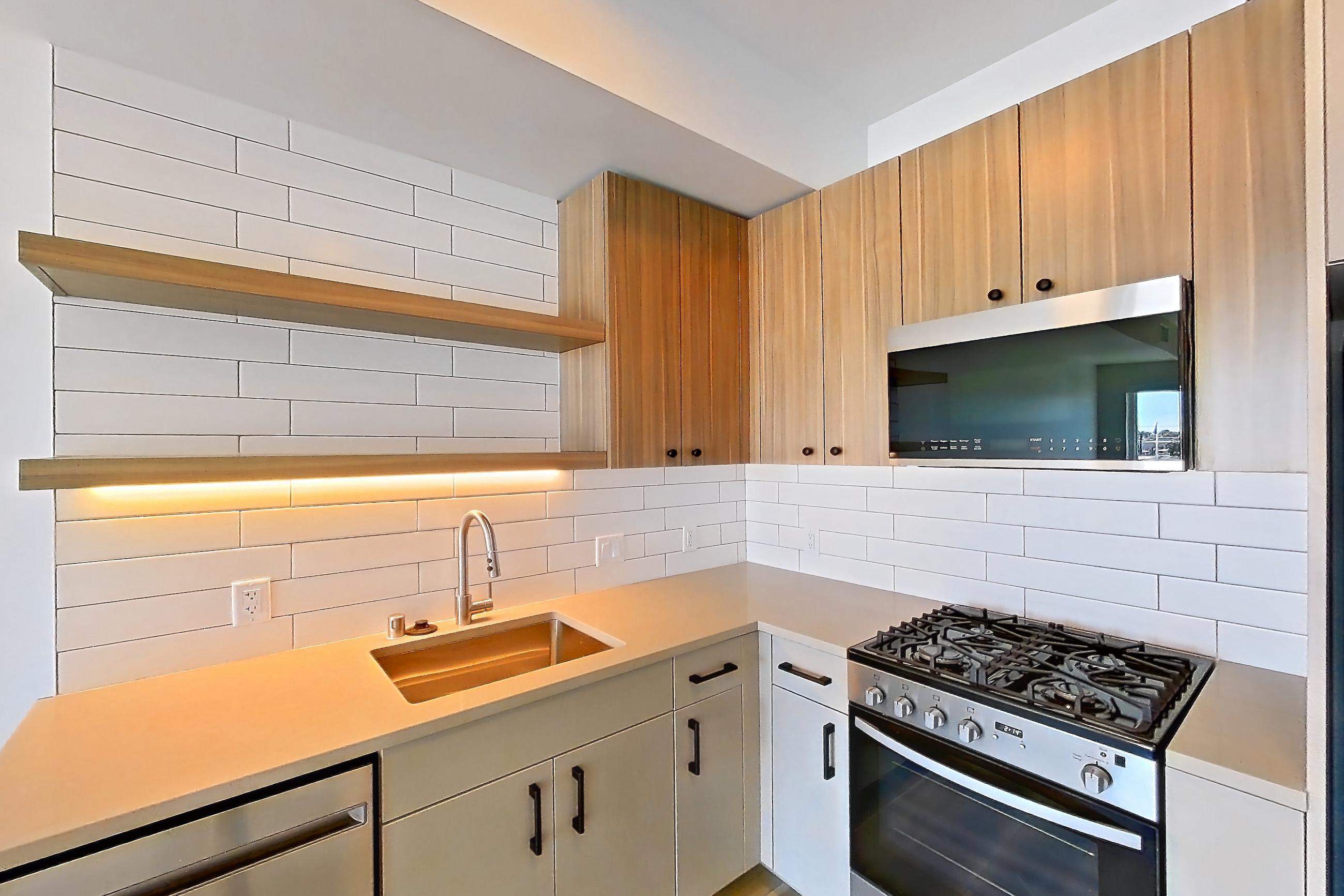 Kitchen with dishwasher, gas range, light countertops, light wood-finish flooring, oven/range, refrigerator, and stainless steel appliances, Apartment 326 at The Myles