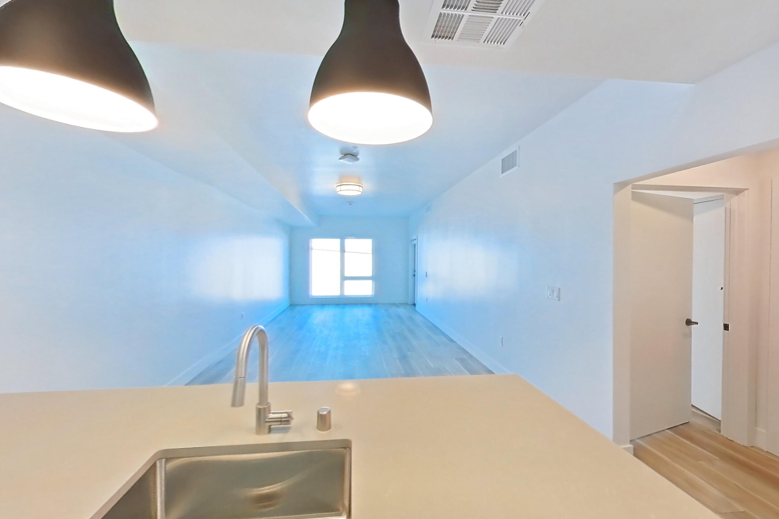 Kitchen with dishwasher, gas range, light countertops, light wood-finish flooring, oven/range, refrigerator, stainless steel appliances, and wood-look tile flooring, Apartment 337 at The Myles