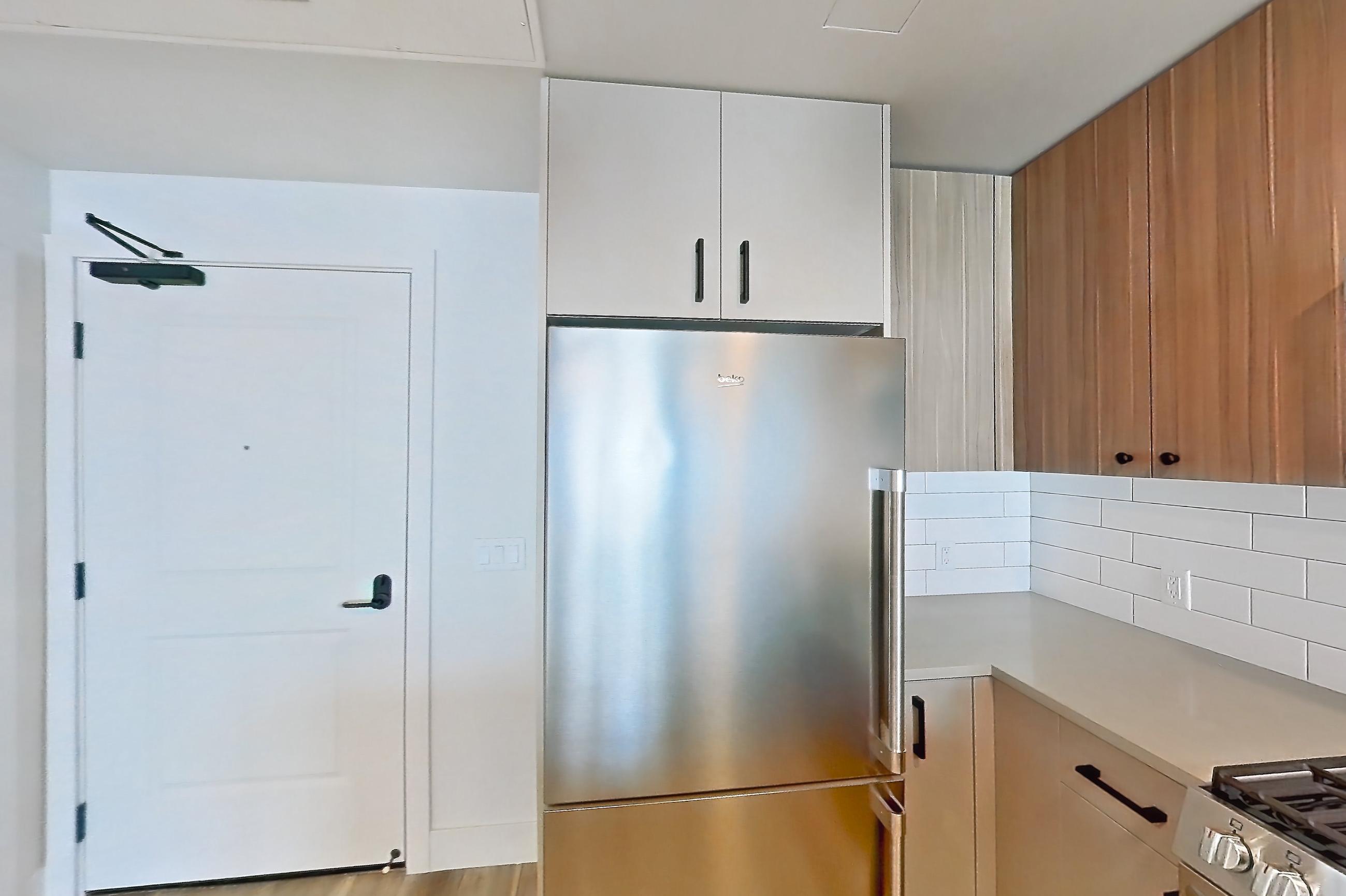 Kitchen with dishwasher, gas range, light countertops, light wood-finish flooring, oven/range, refrigerator, stainless steel appliances, and wood-look tile flooring, Apartment 337 at The Myles
