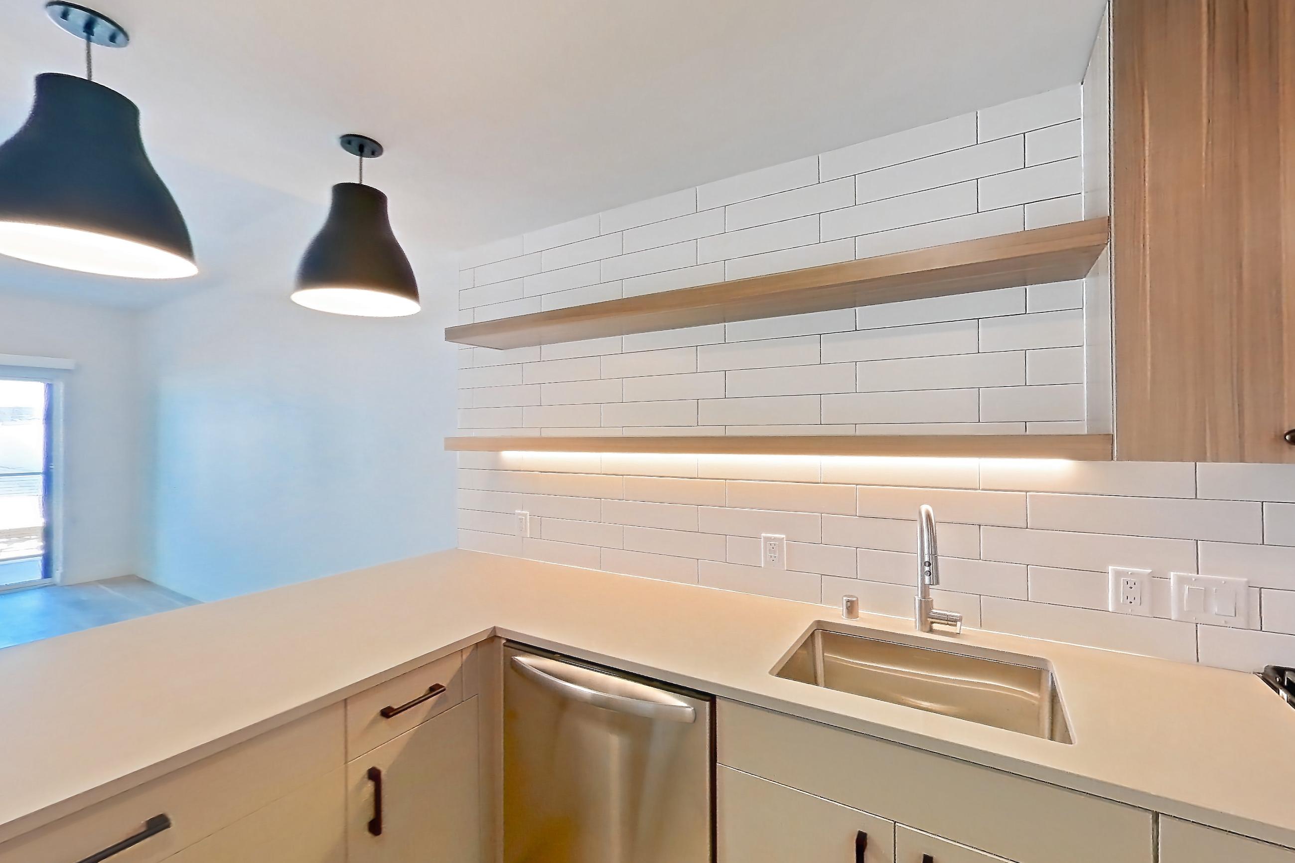 Kitchen with dishwasher, gas range, light countertops, light wood-finish flooring, microwave, oven/range, refrigerator, and stainless steel appliances, Apartment 341 at The Myles