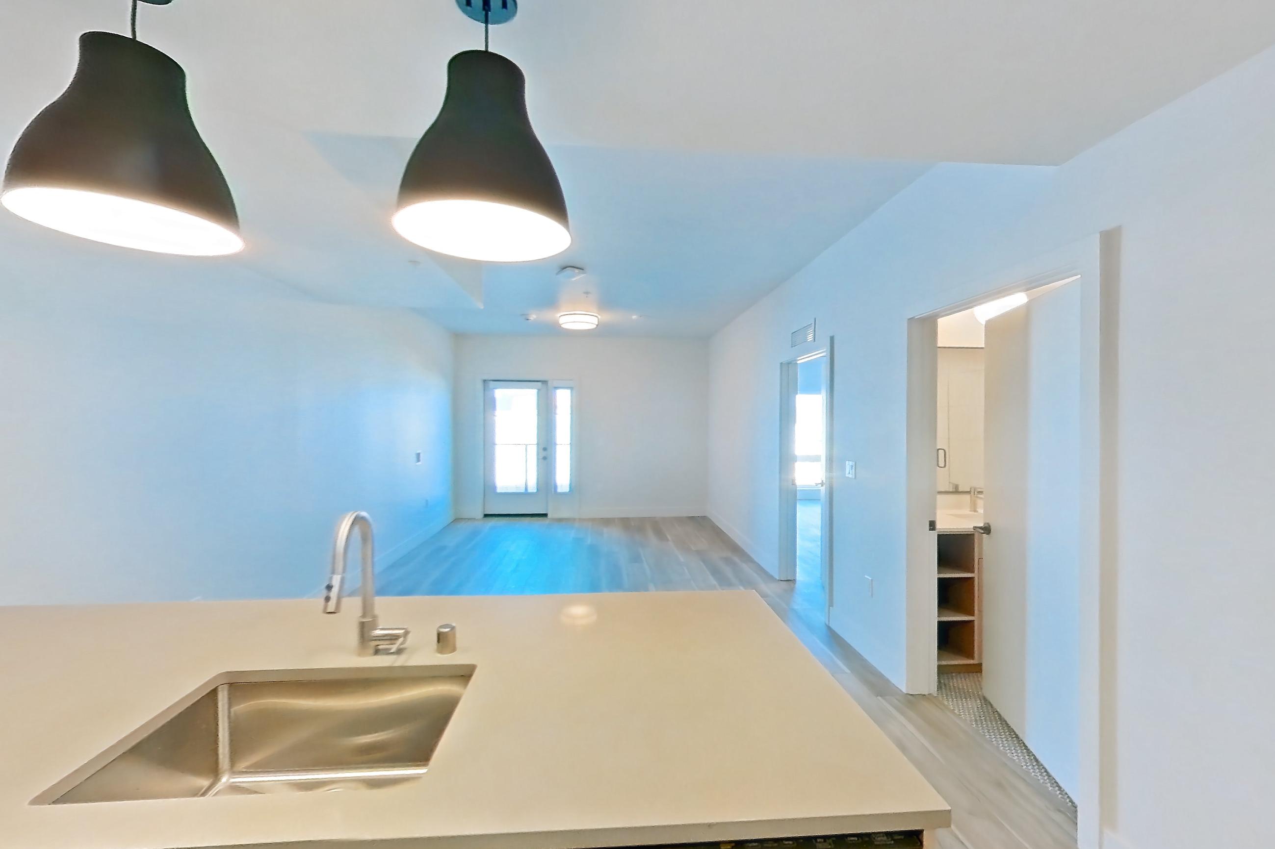 Kitchen with dishwasher, gas range, light countertops, light wood-finish flooring, oven/range, refrigerator, stainless steel appliances, and wood-look tile flooring, Apartment 347 at The Myles