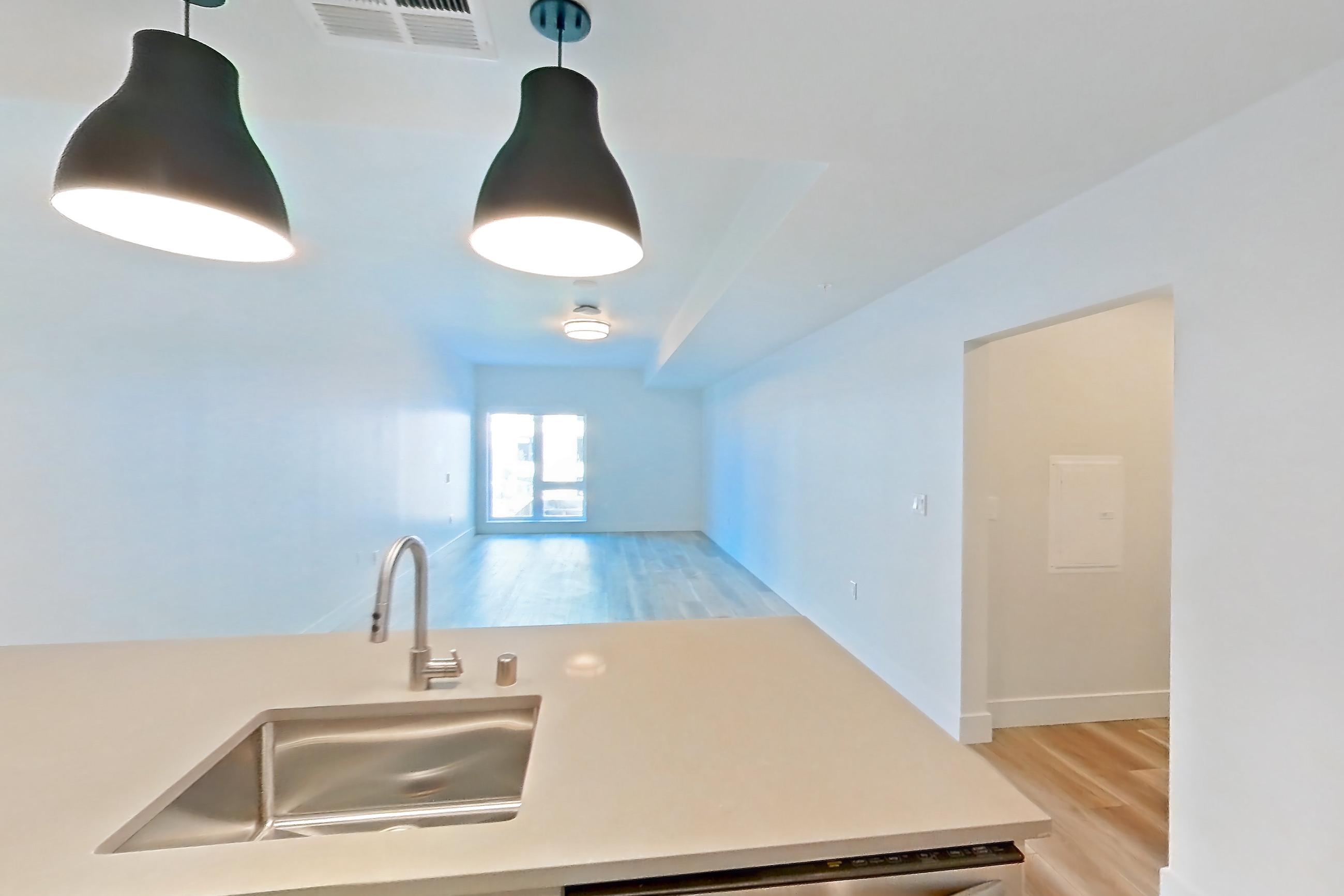 Kitchen with dishwasher, gas range, light countertops, light wood-finish flooring, oven/range, refrigerator, and stainless steel appliances, Apartment 402 at The Myles