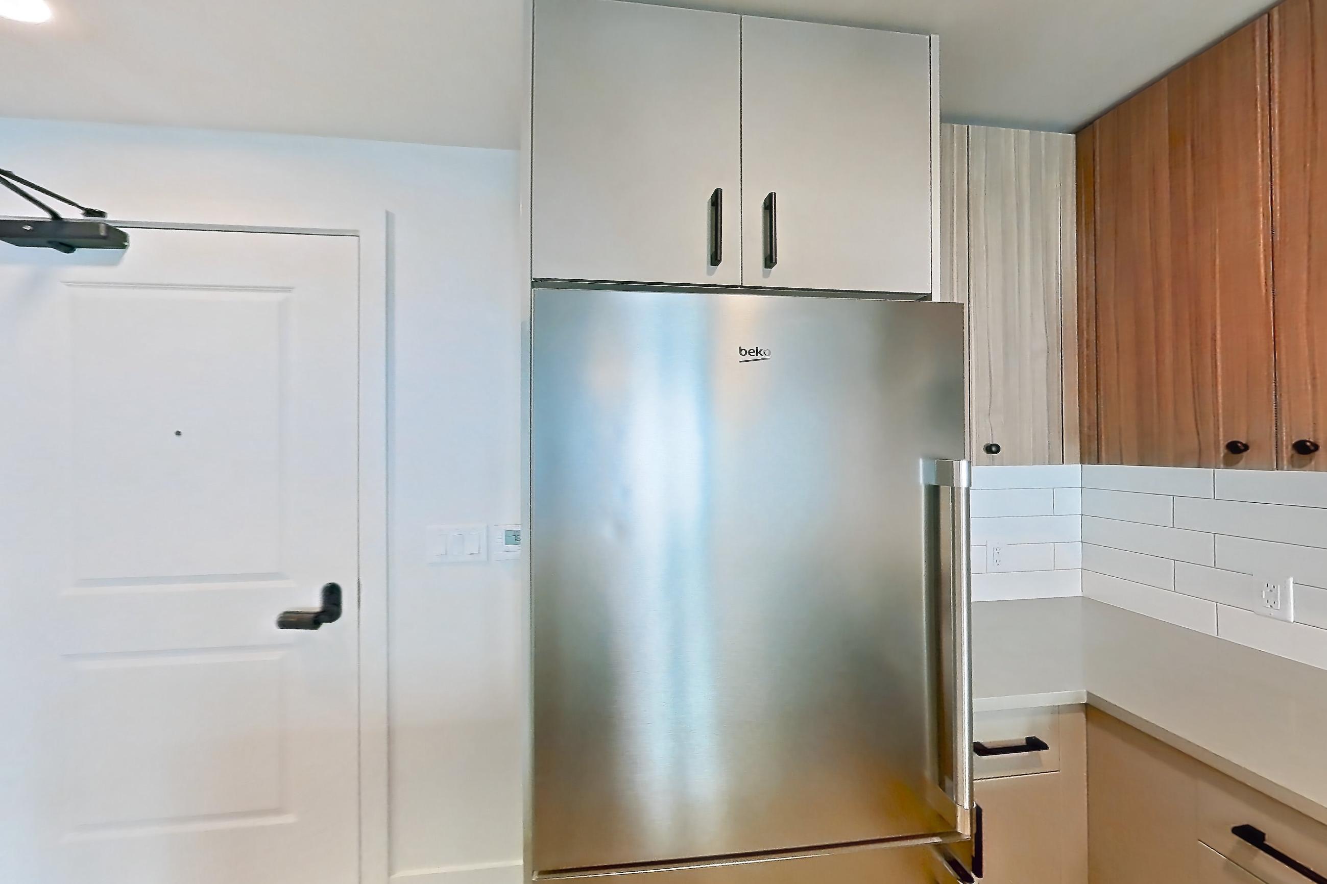Kitchen with dishwasher, gas range, light countertops, light wood-finish flooring, oven/range, refrigerator, and stainless steel appliances, Apartment 402 at The Myles